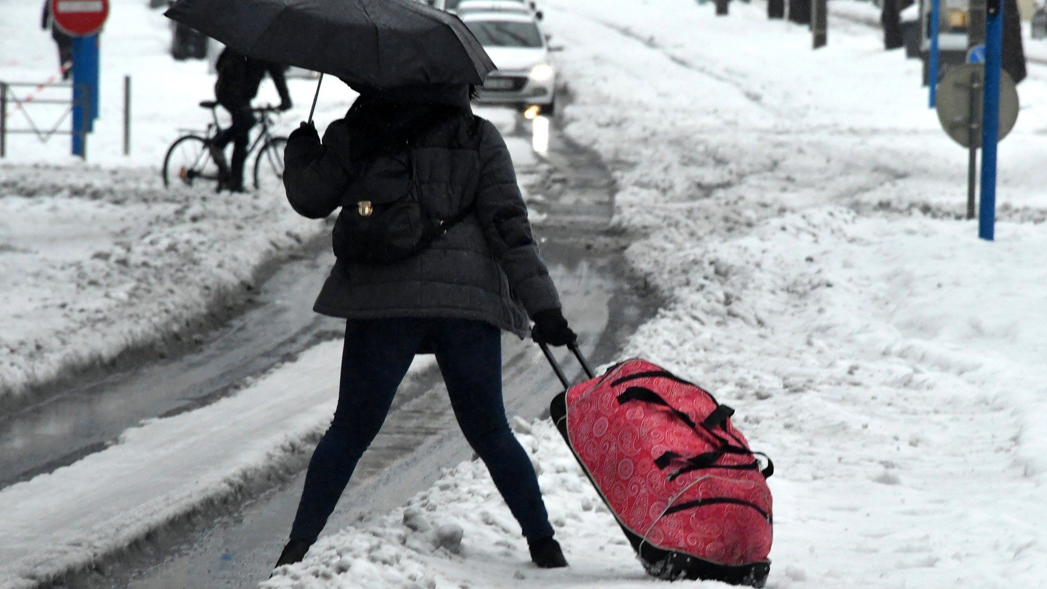A woman struggles with a bag as she walks down a snow-covered street in Montpellier, southern France