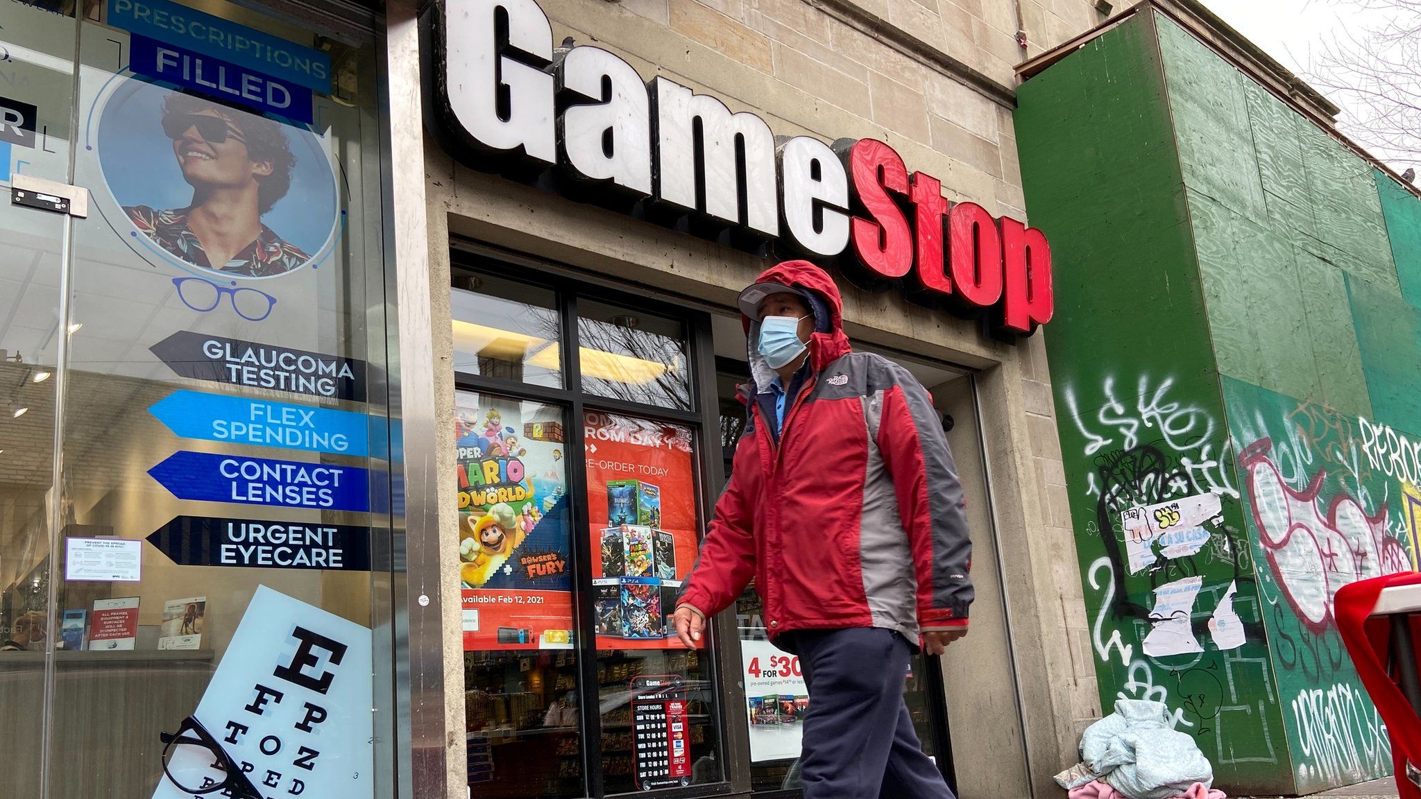 A man in a mask walks past a GameStop store in NY