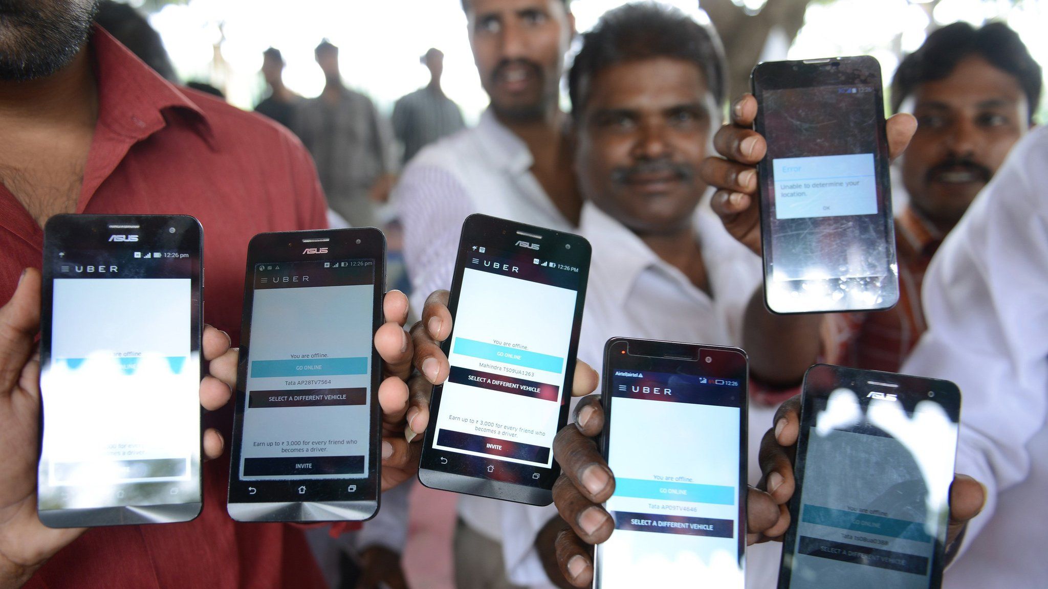 Indian drivers for Uber show mobiles phones given to them by the company
