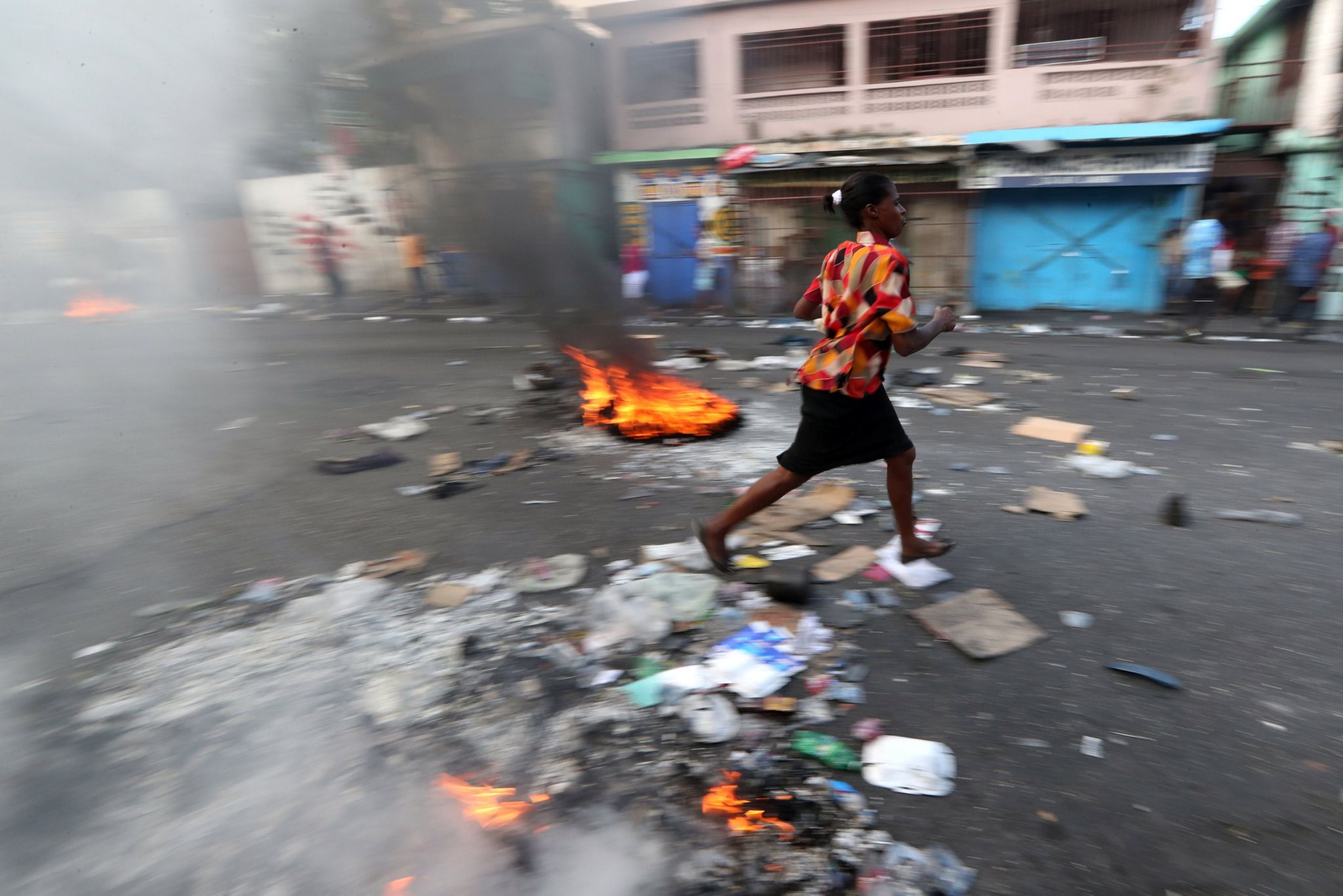 A woman walks past a burning barricade during anti-government protests in Port-au-Prince