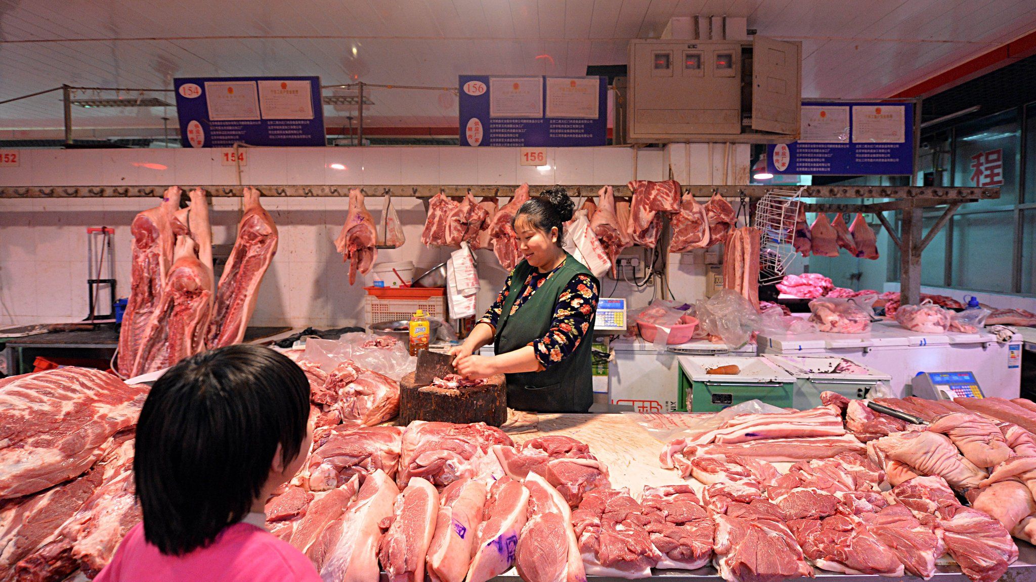 Chinese butcher preparing slabs of pork for sale at a market in Beijing