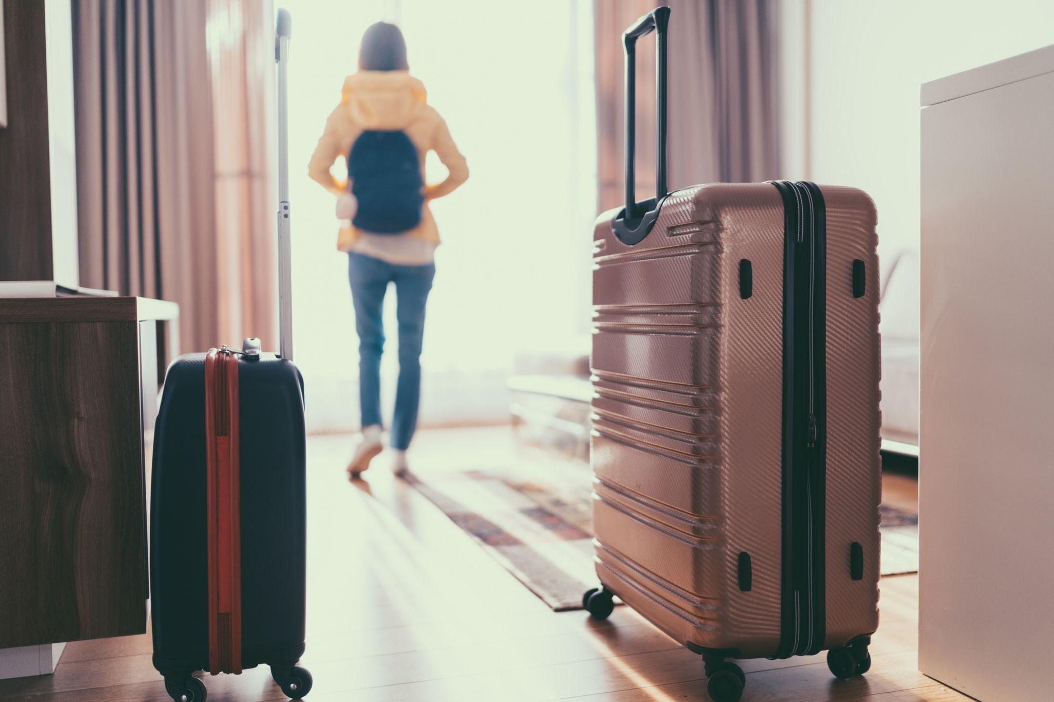 Woman who has just entered hotel room with suitcases