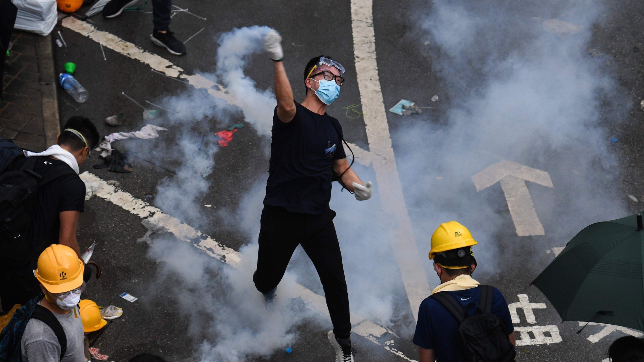 A protester throws back a tear gas during clashes with police outside the government headquarters in Hong Kong on June 12, 2019.