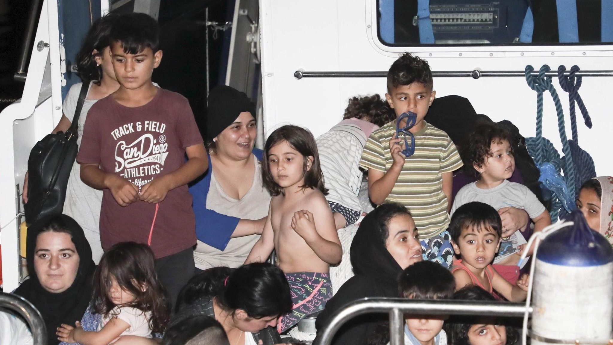 Italian Coast Guard and medical staff escort Iraqi Kurdish migrants off a Coast Guard patrol boat in the port of Crotone, Italy - 13 July 2018