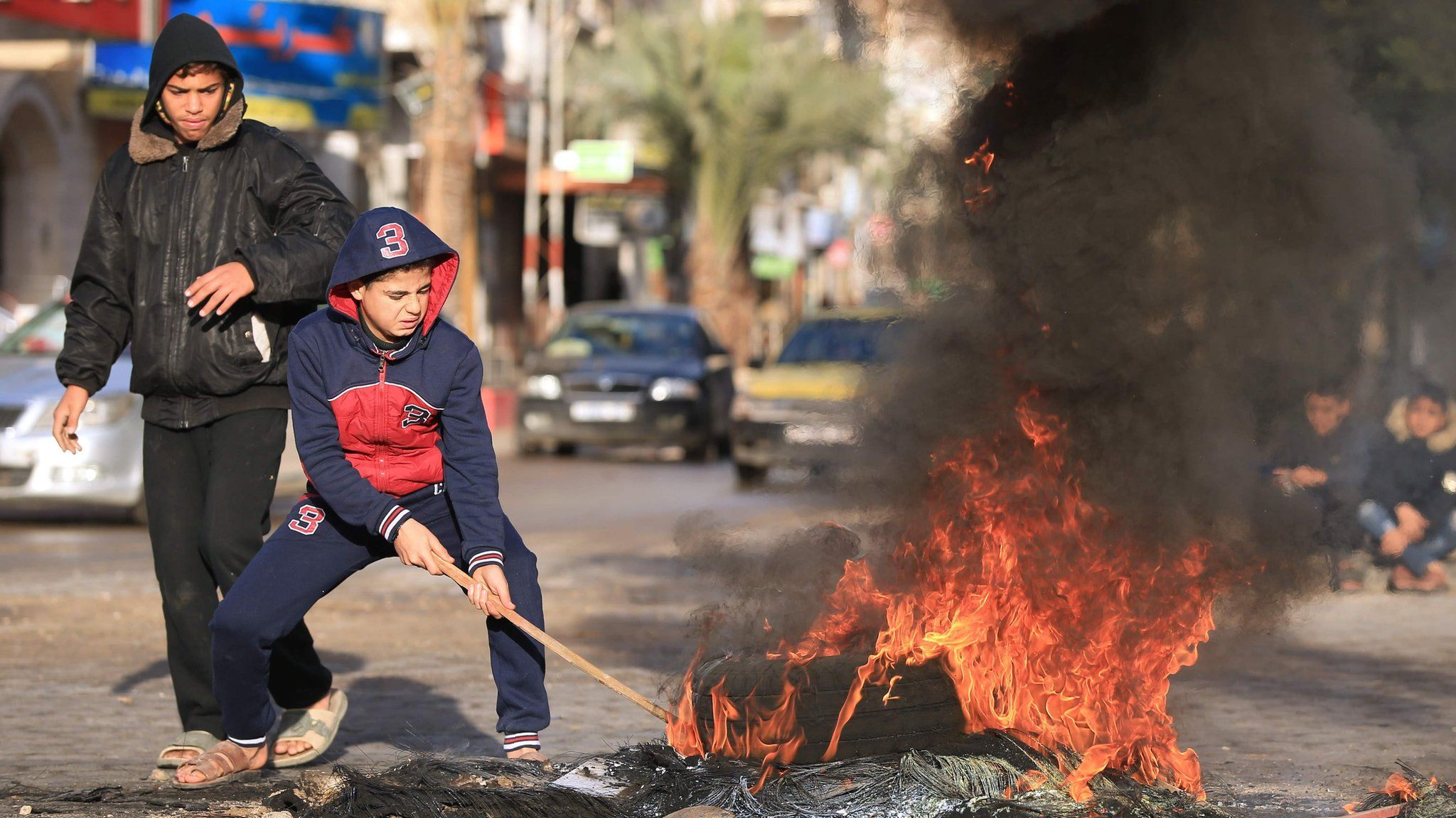 Palestinian youths set tyres on fire in Gaza City on 7 December 2017