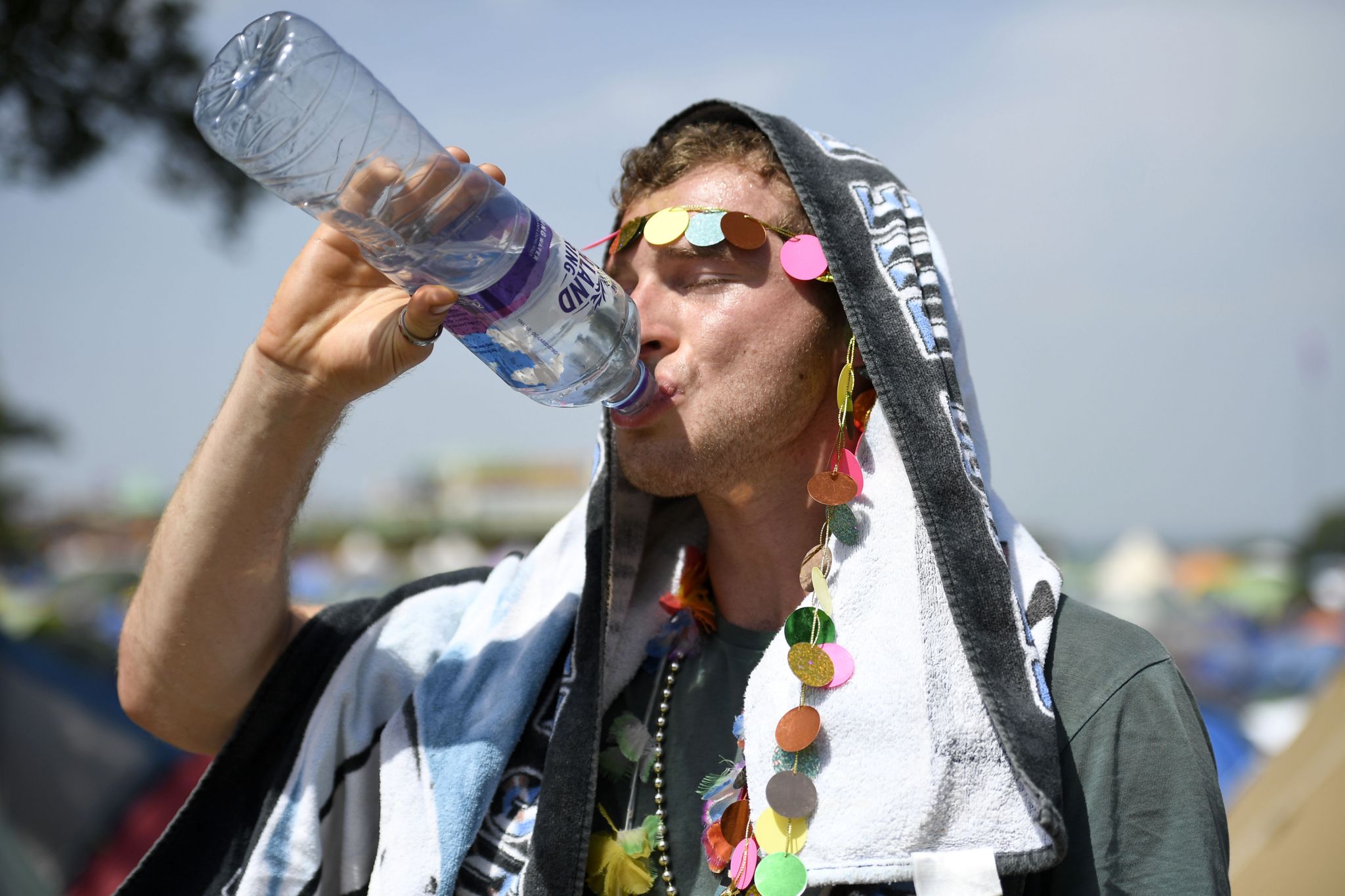 A festival-goer drinks water in the heat at Glastonbury