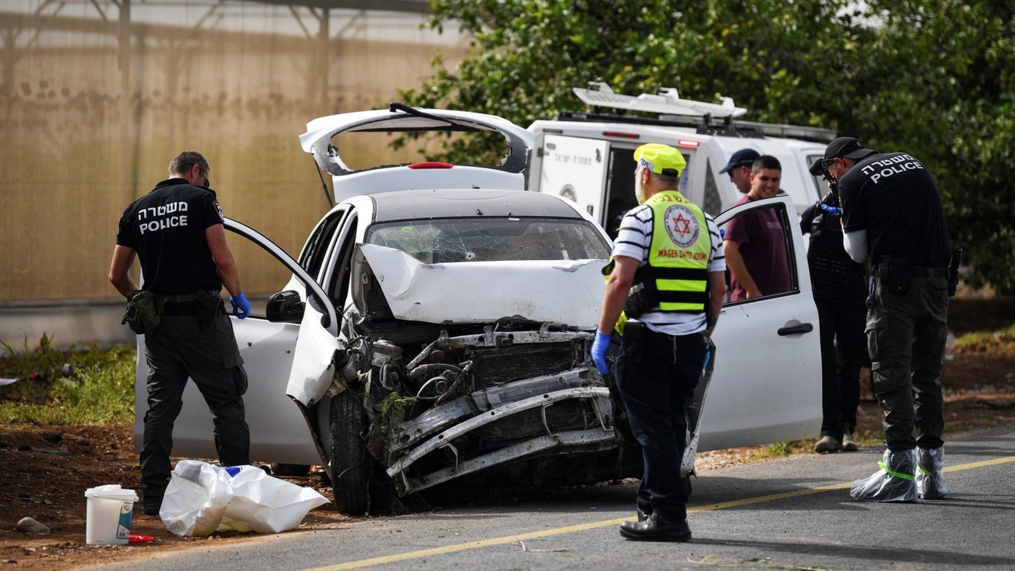 Israeli medics and police check a damaged car at the scene of a shooting attack in the Jordan Valley in the Israeli-occupied West Bank (7 April 2023)
