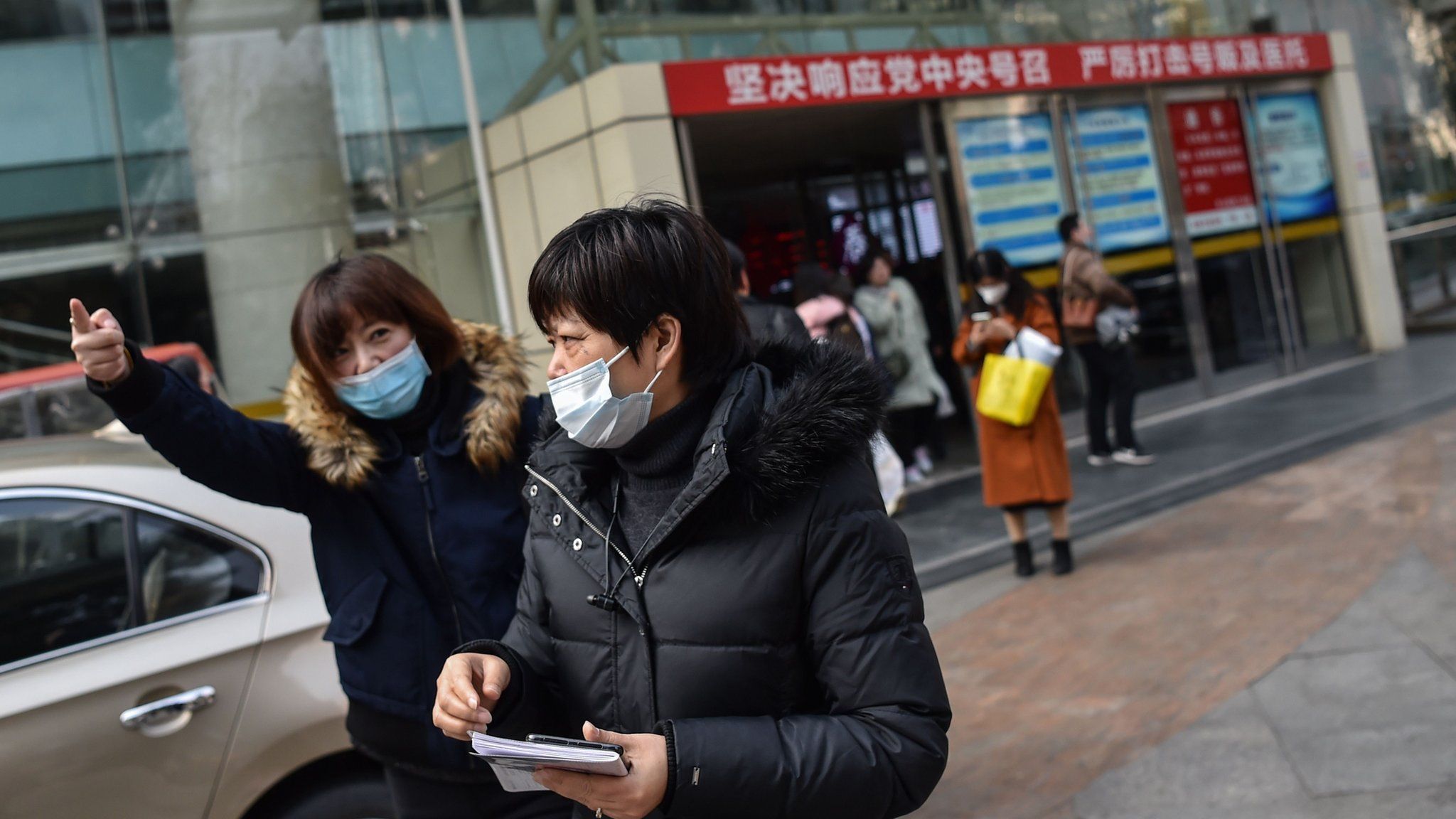 Two women wear protective masks in front of a hospital in Shanghai