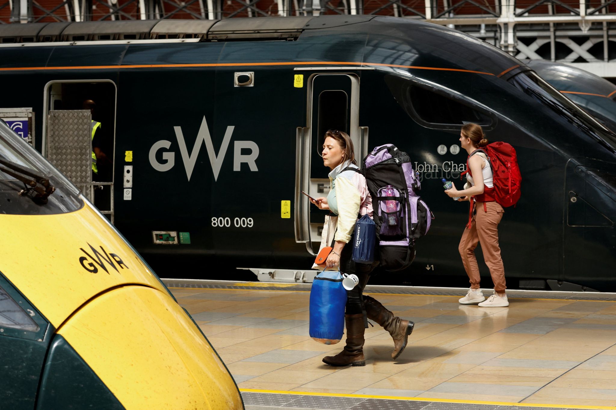A traveller with camping equipment walks at Paddington Station