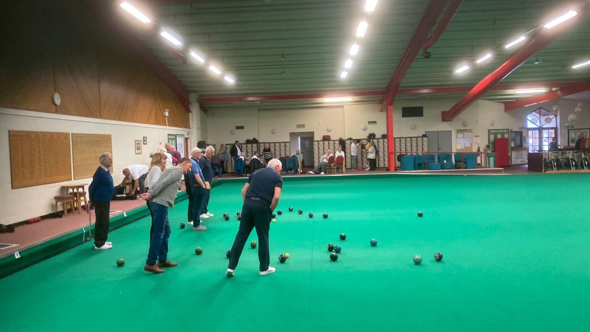 Group of men and women playing bowls on a large indoor mat