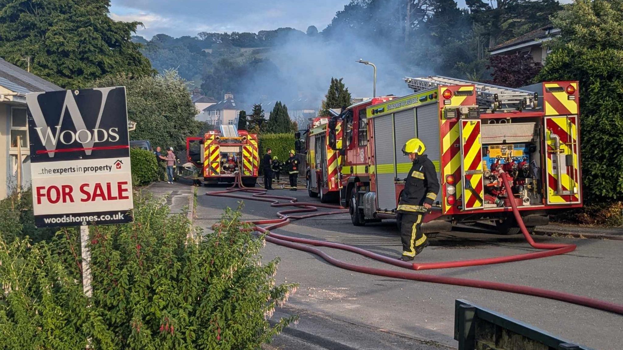 Fire engines and firefighters on the scene of a fire which broke out at a bungalow in Totnes, with smoke seen behind the fire engines