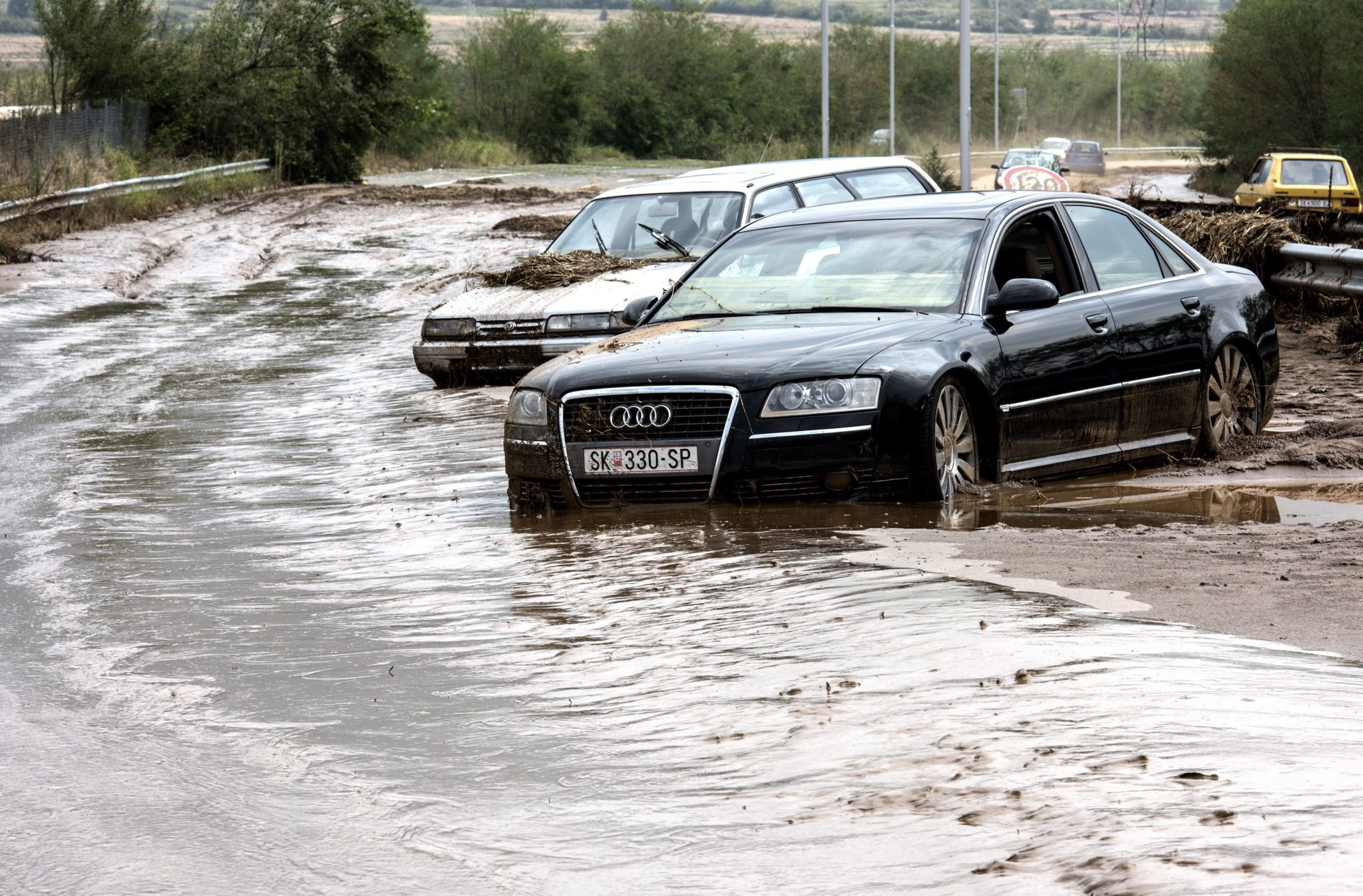 cars stuck in the mud next to flooded ring road