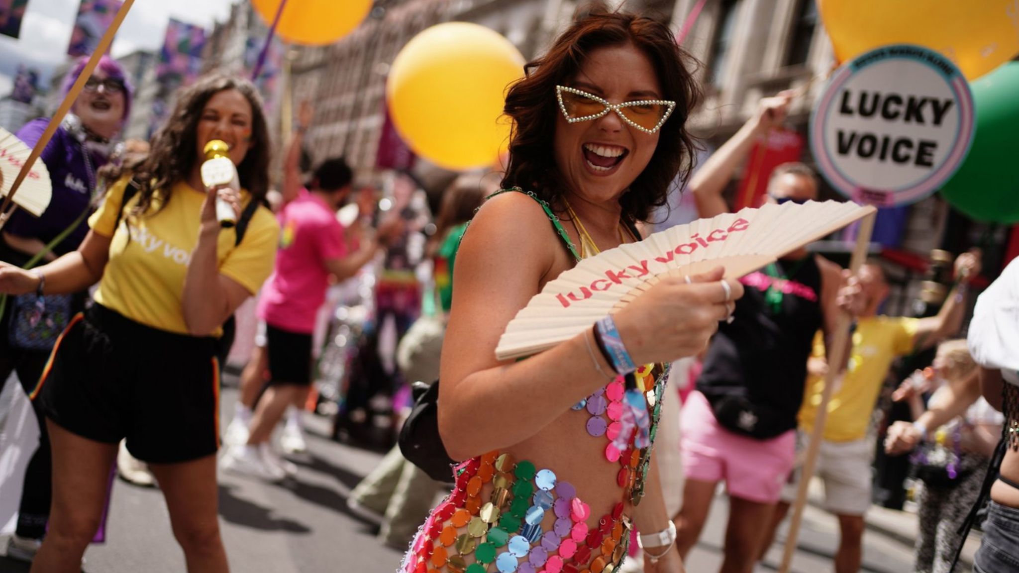Woman waves a fan on Piccadilly during Pride march
