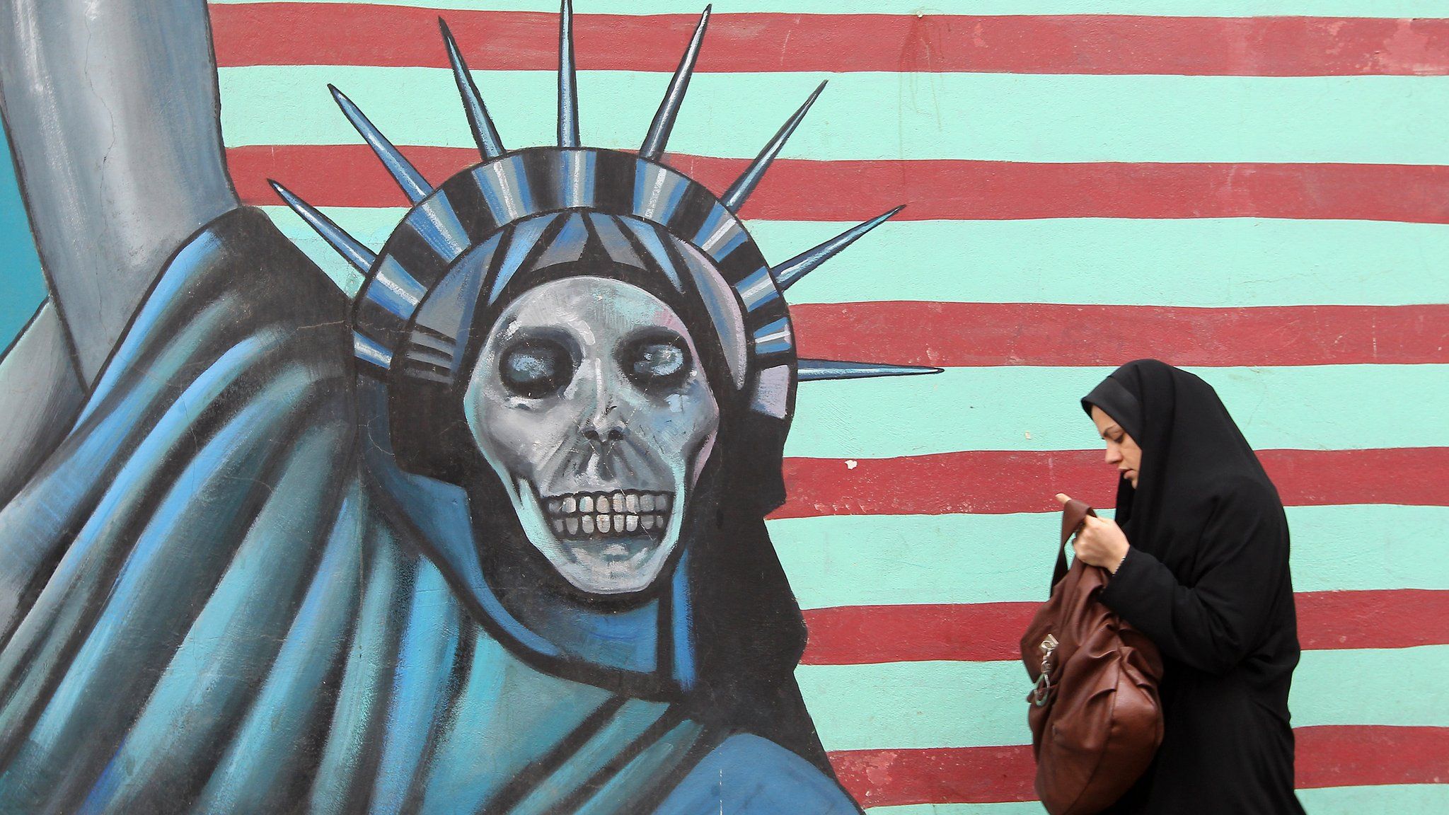 An Iranian woman walks past an anti-US mural painted on the wall of the former US embassy in Tehran in November 2011