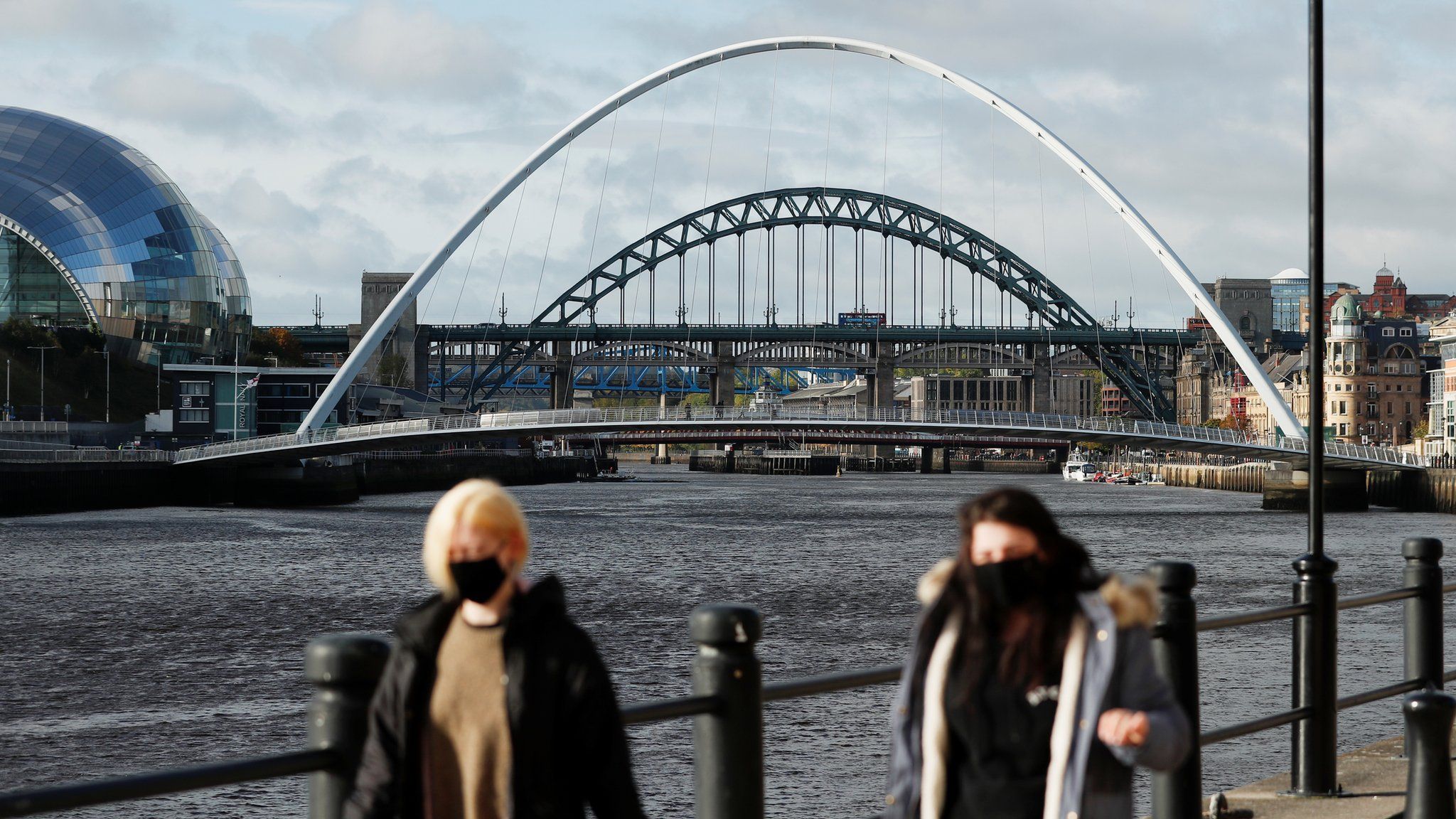 View of two women wearing masks with River Tyne bridges and the Sage Gateshead in the background