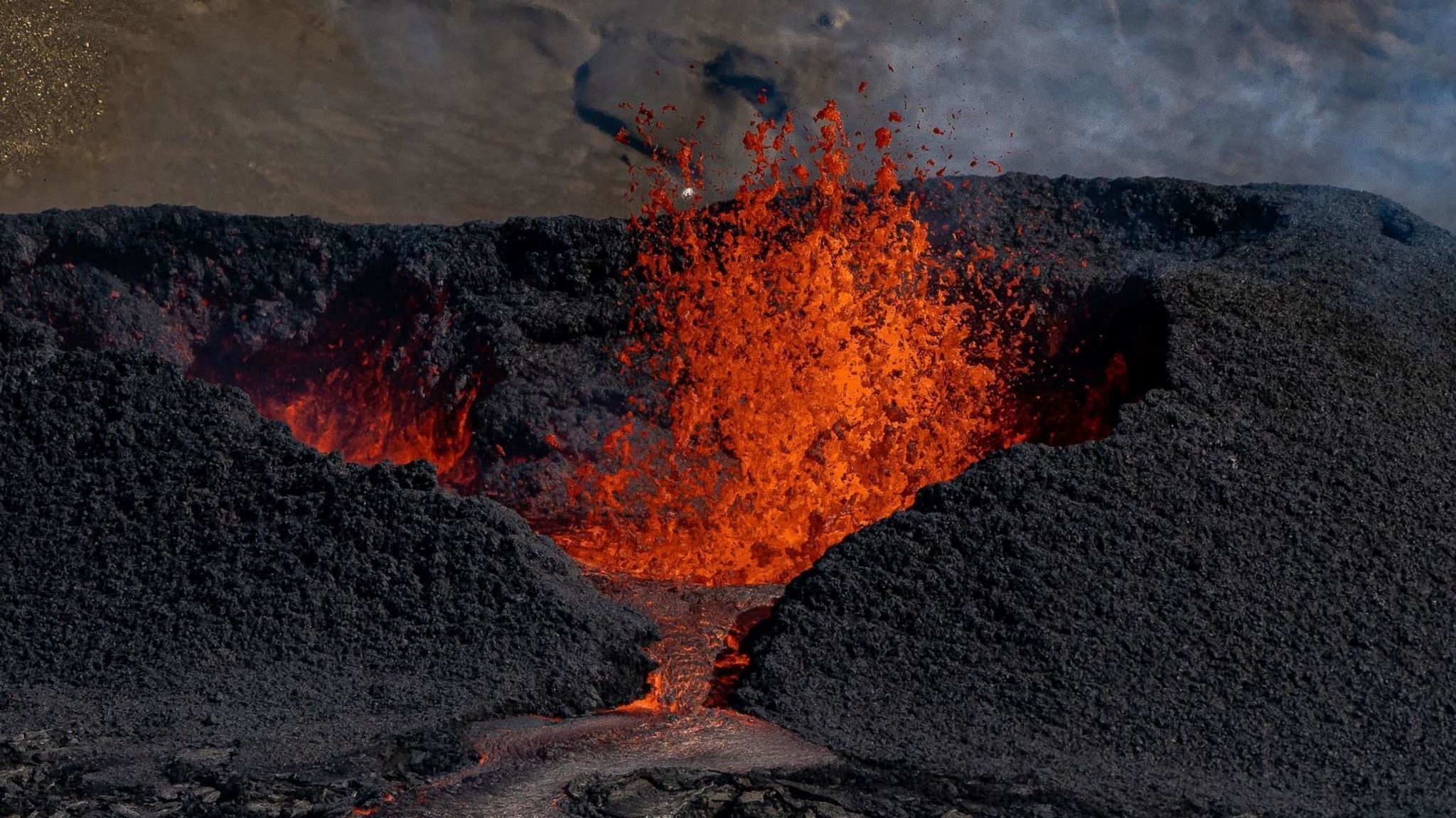 Tourists visit a heart shaped crater as lava flows from the volcano in Fagradalsfjall, Iceland,