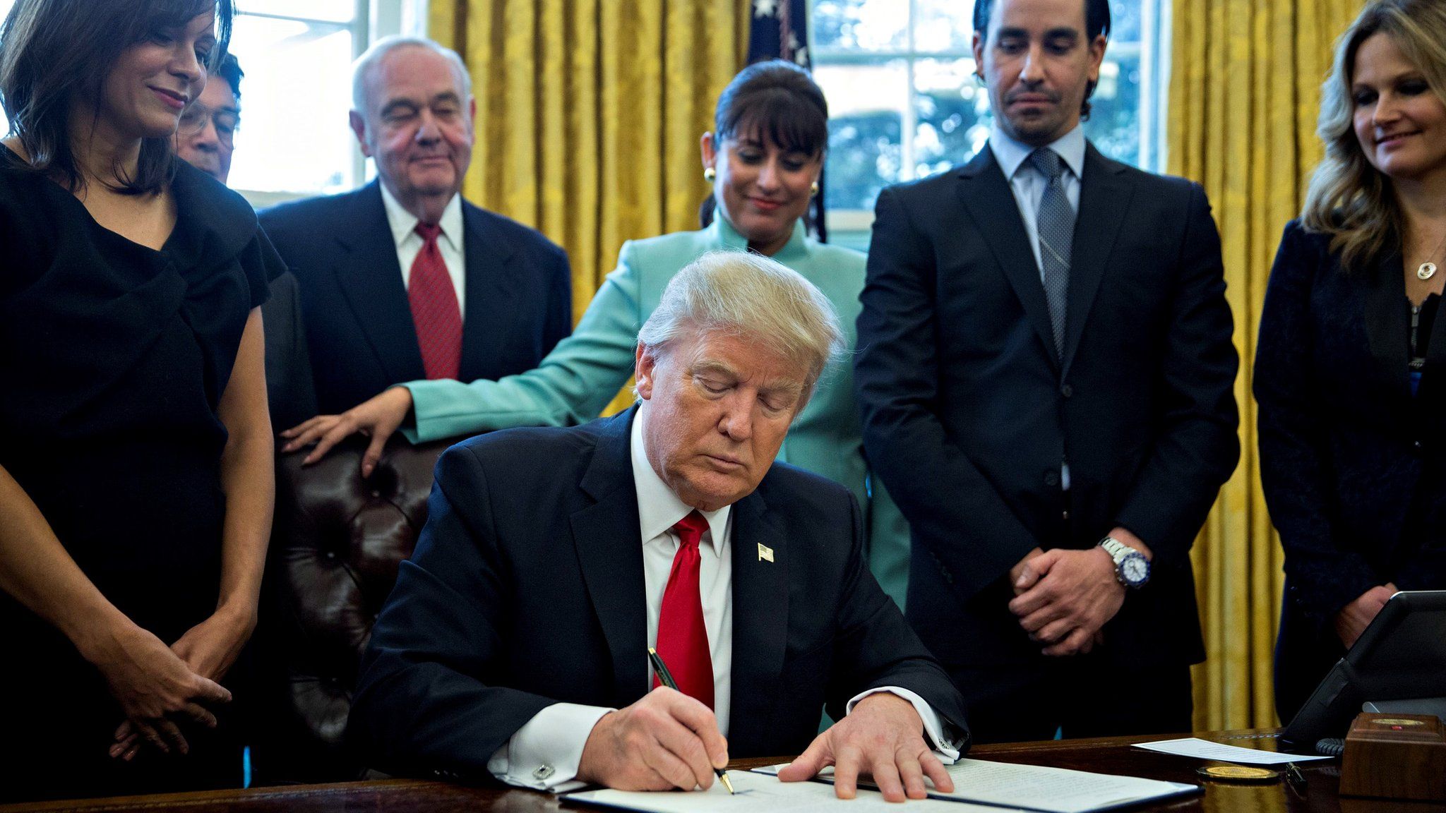 US President Donald Trump (C) signs an executive order while surrounded by small business leaders in the Oval Office of the White House in in Washington, D.C., US, 30 January 2017.