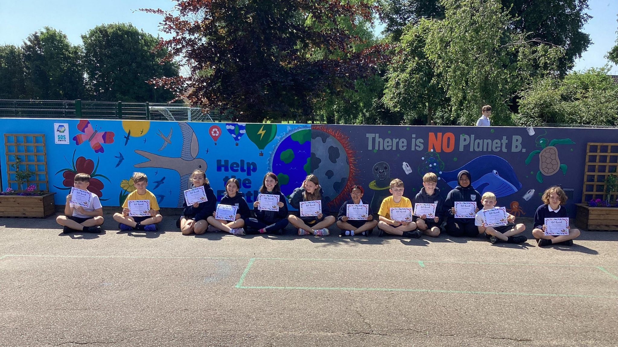 School students sitting in front of their artwork