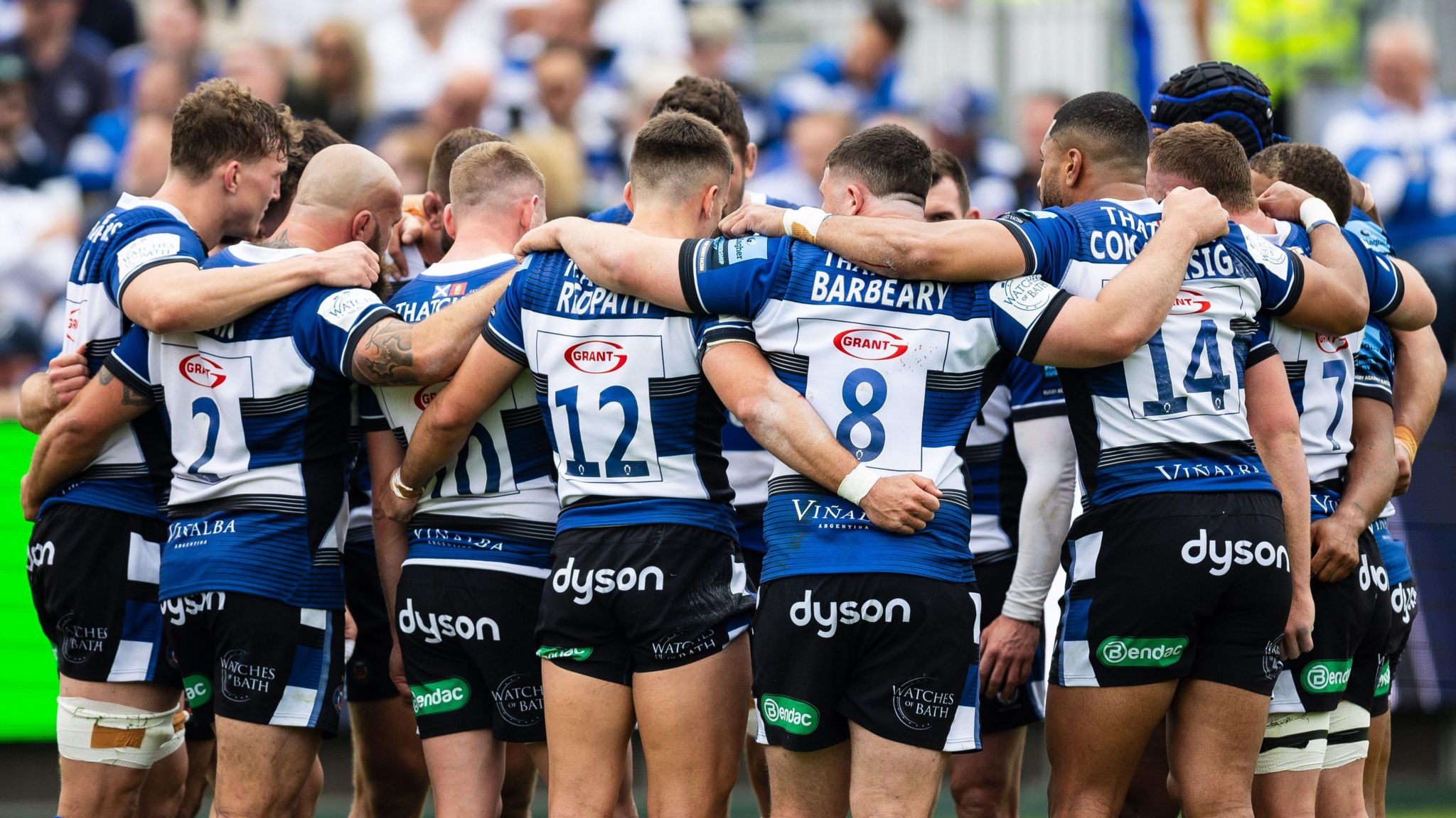 Bath players hold their arms around each other in a huddle after full-time