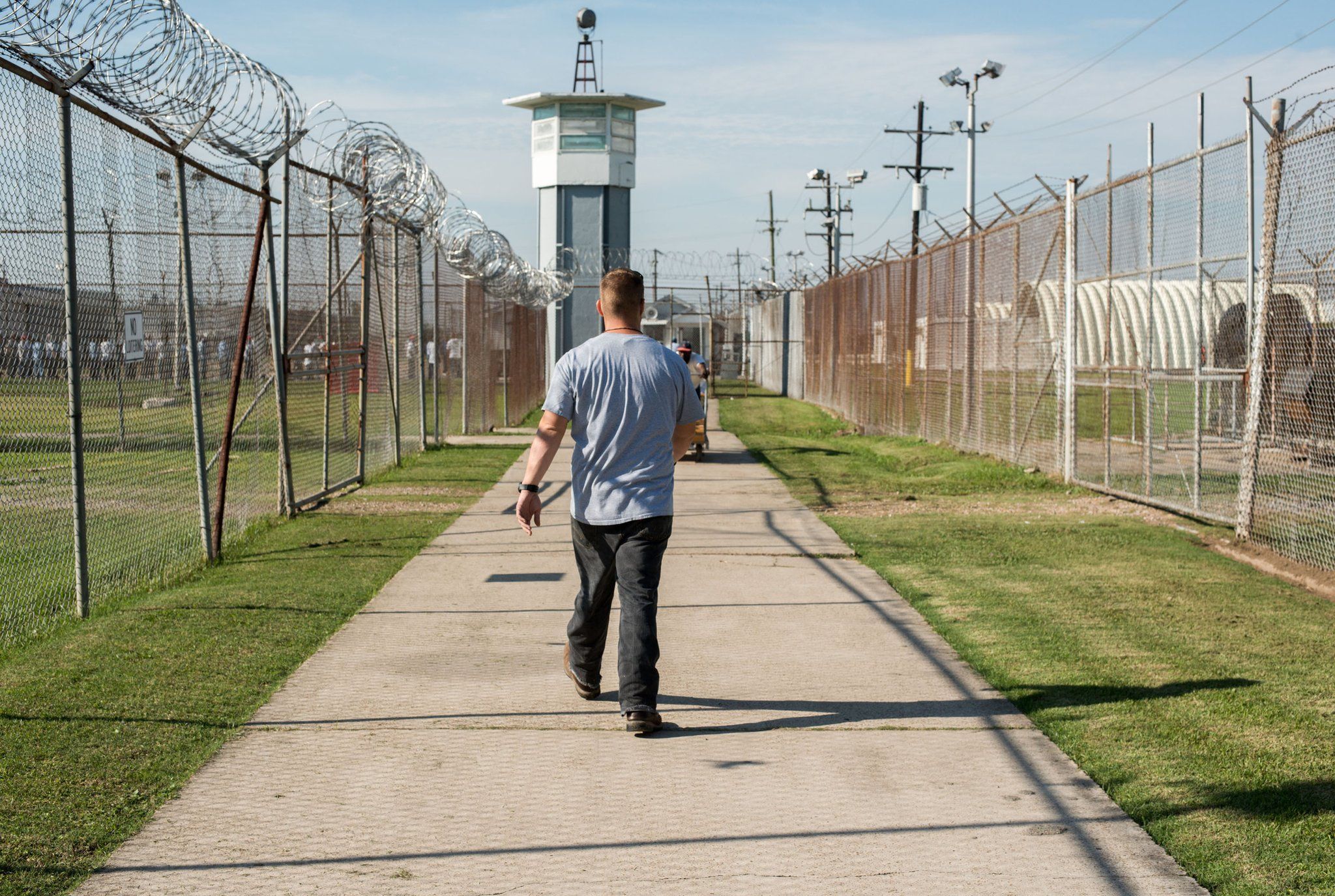 A prisoner walks through a fenced section toward a guard tower at Louisiana State Penitentiary, also known as Angola