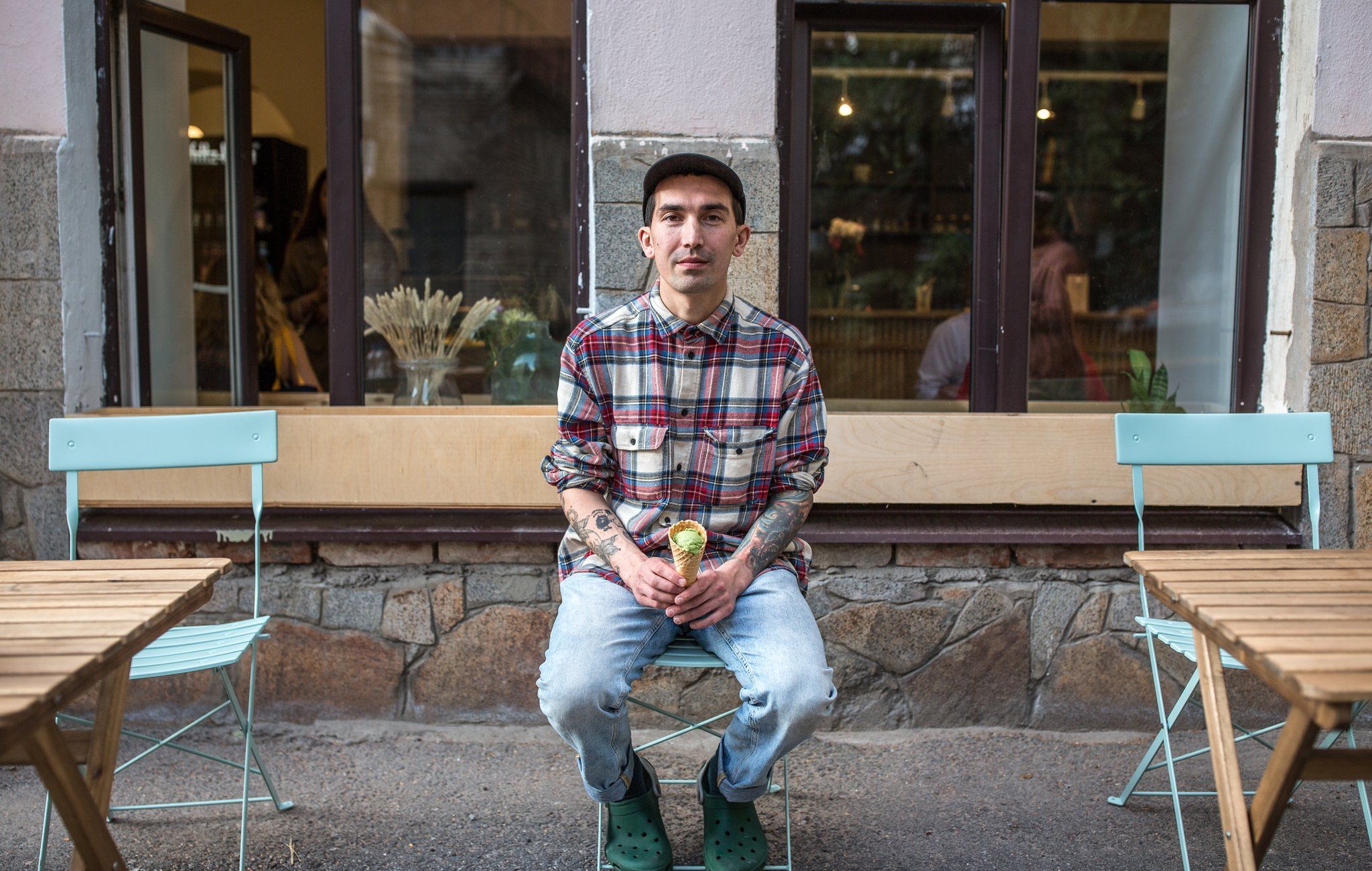 Slava sitting outside his cafe, Fika, holding a green matcha flavoured ice cream in a cone