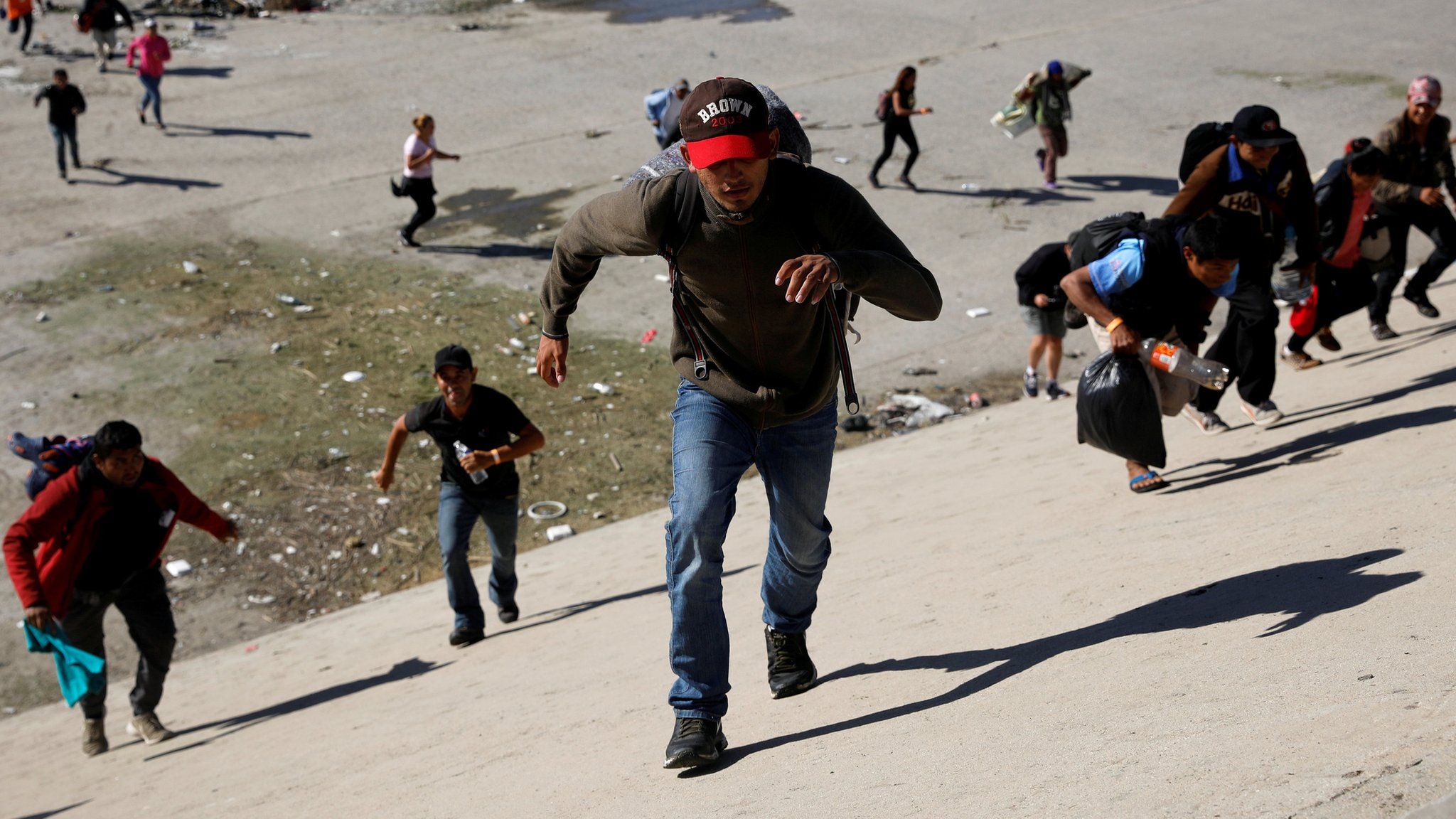 Migrants, part of a caravan of thousands traveling from Central America en route to the United States, run across the Tijuana river