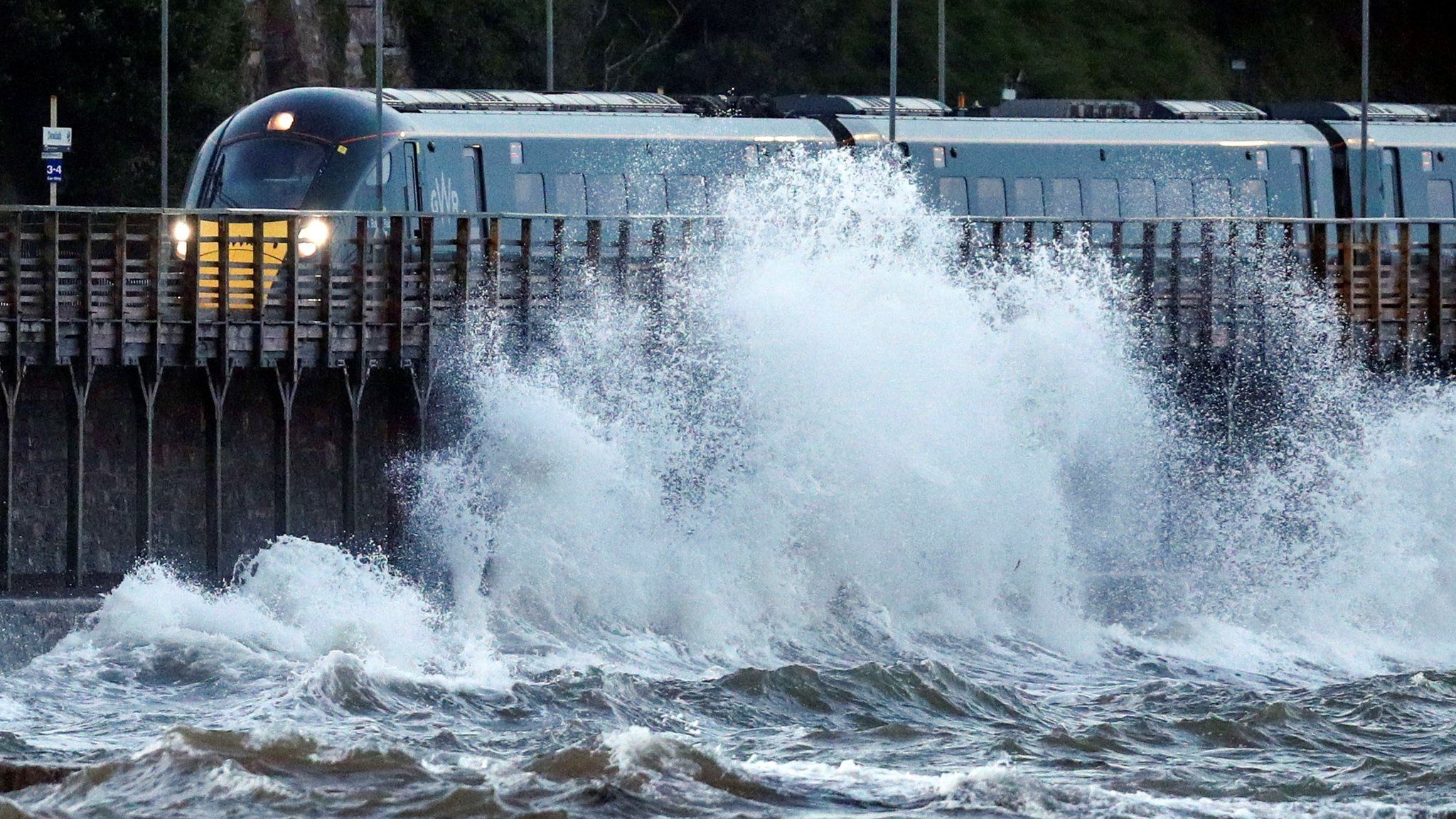 A train passes by strong waves in Dawlish, Devon