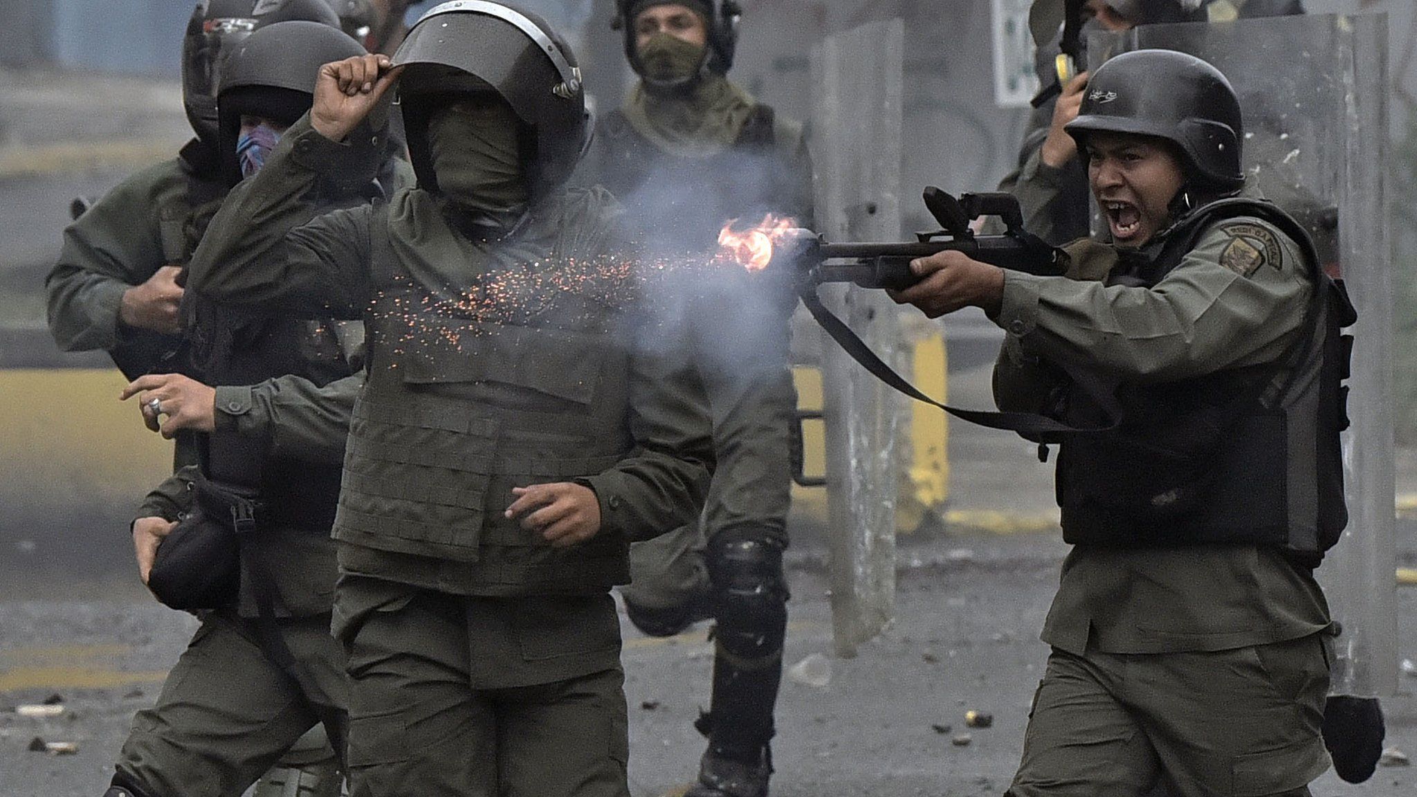 A member of the national guard fires his shotgun at opposition demonstrators during clashes in Caracas on July 28, 2017
