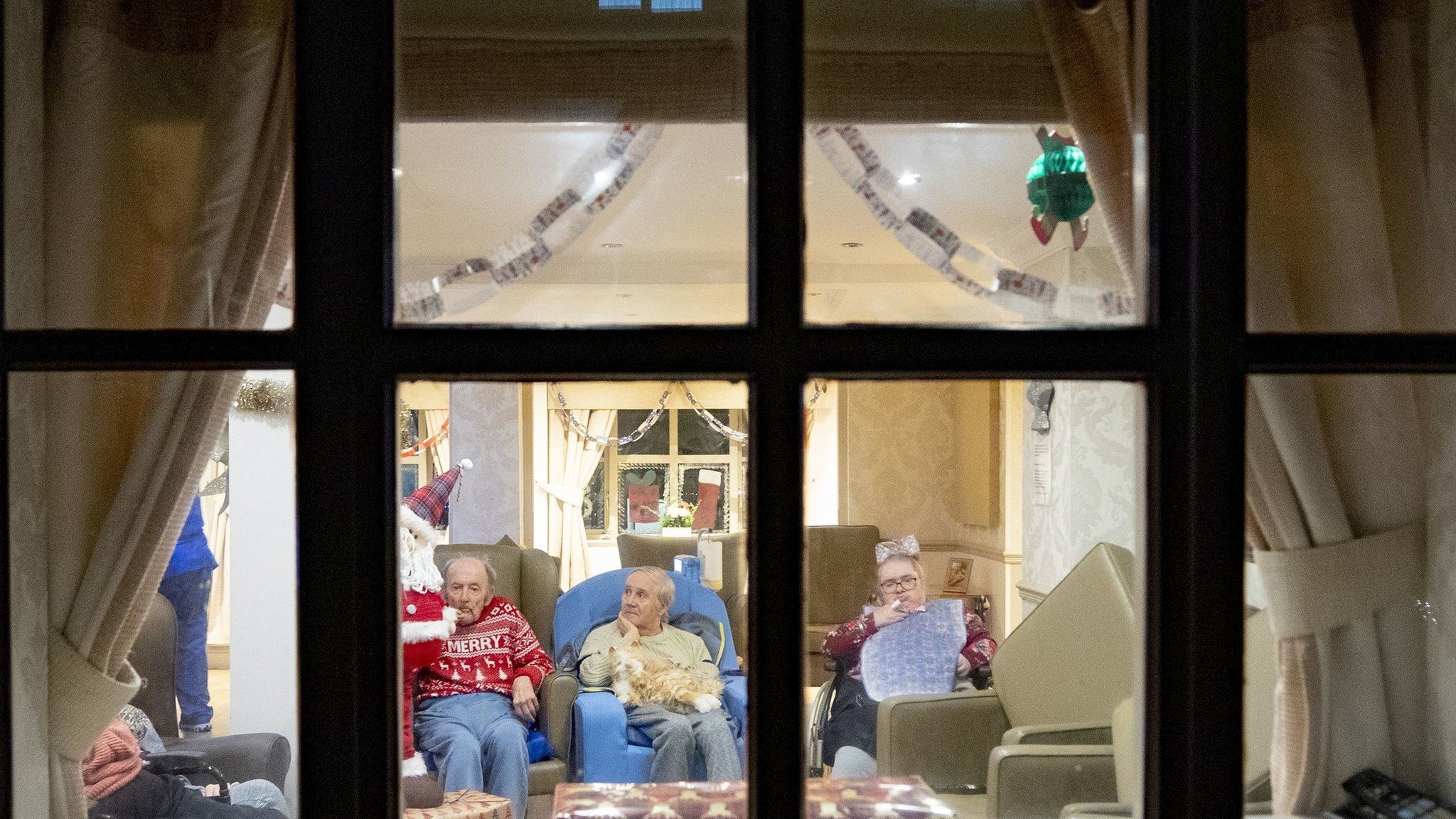 Residents of a care home in Liverpool seen through a window