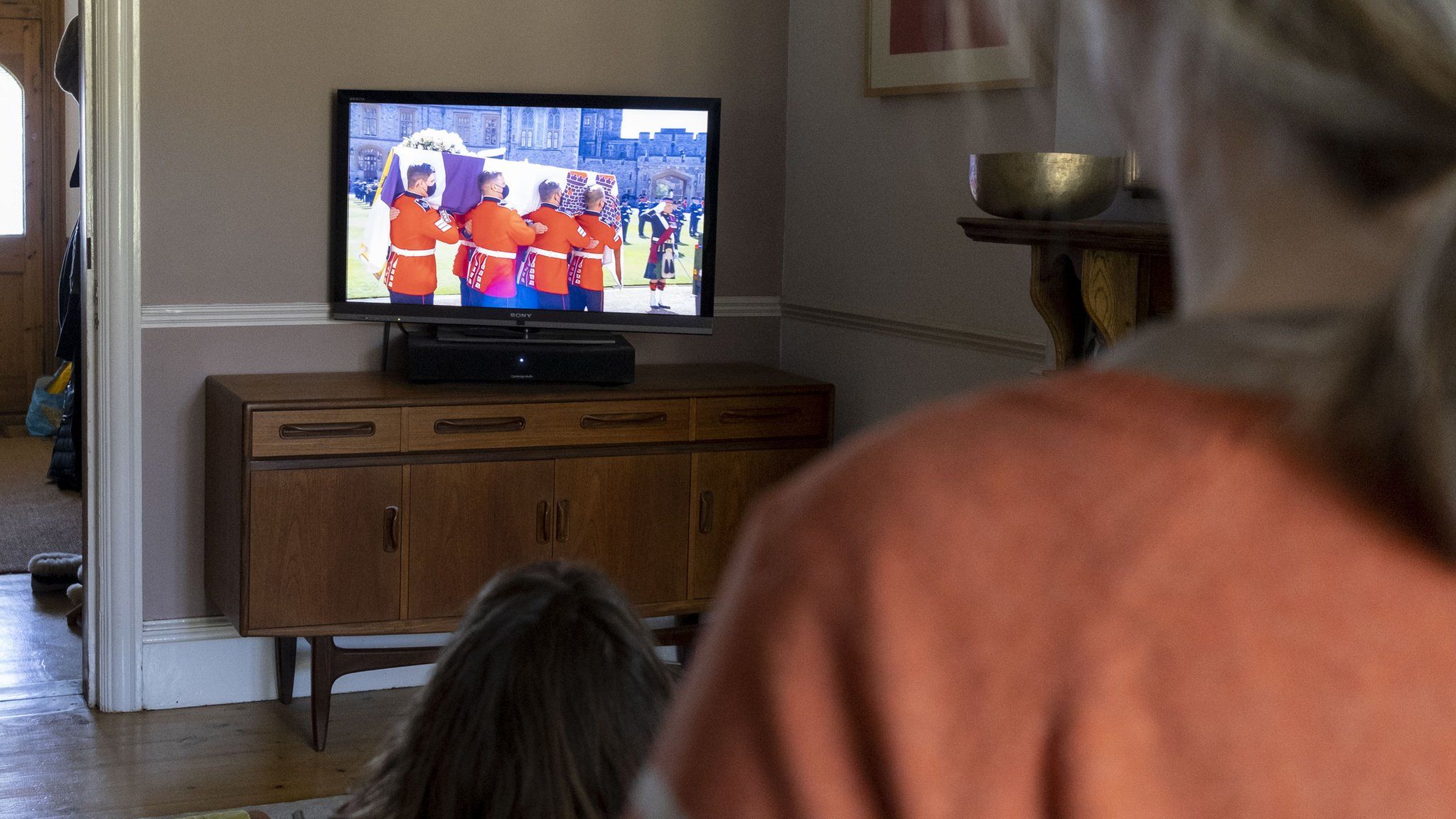 The funeral of Prince Philip, the Duke of Edinburgh, and husband to Queen Elizabeth II, is broadcast on British TV from Windsor Castle and watched in the living room by a south London family