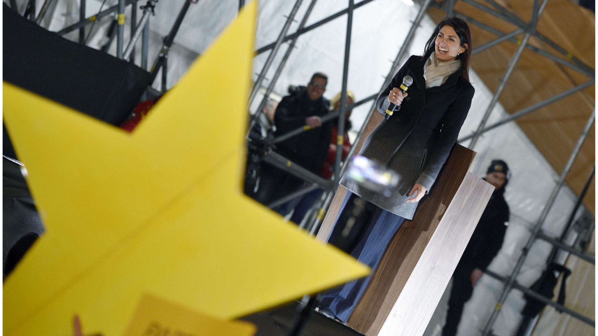 Large gold star is seen in the foreground as Five Star Movement mayor of Rome, Virginia Raggi, addresses supporters in Rome (March 2, 2018)