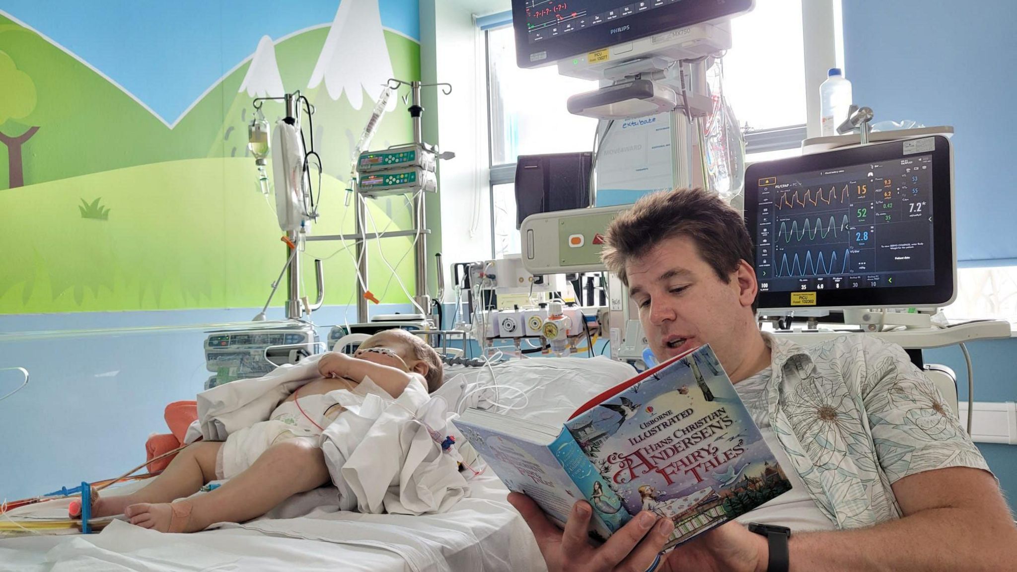 A dad reading to his baby son in hospital