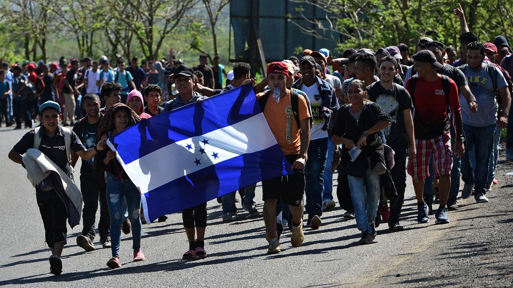 Honduran migrants walk with a Honduran national flag heading to Puerto Barrios, in Izabal department, Guatemala