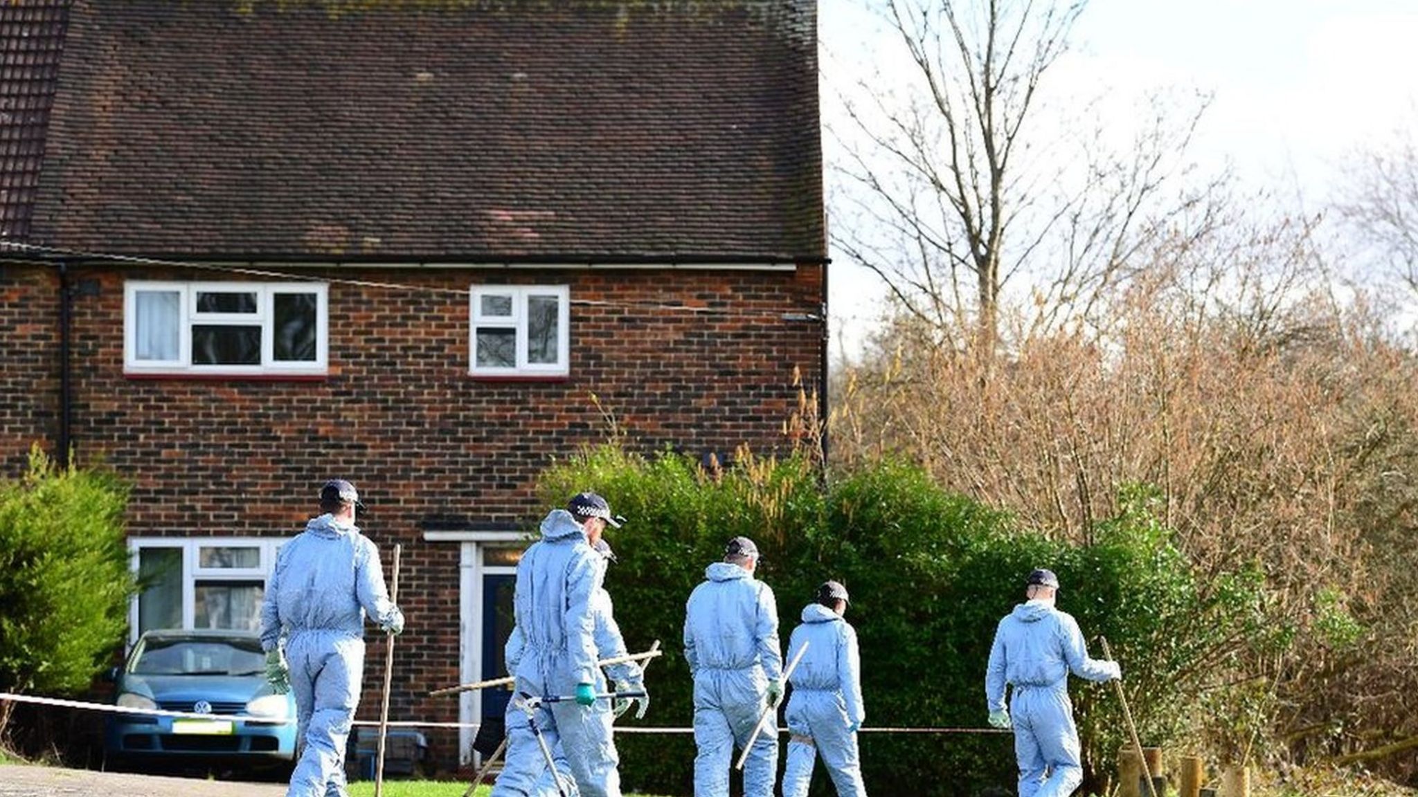 Forensic officers by trees near crime scene