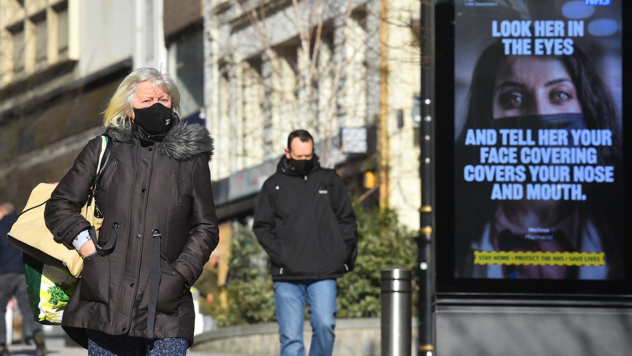 A woman walks past a coronavirus sign in Bradford City Center