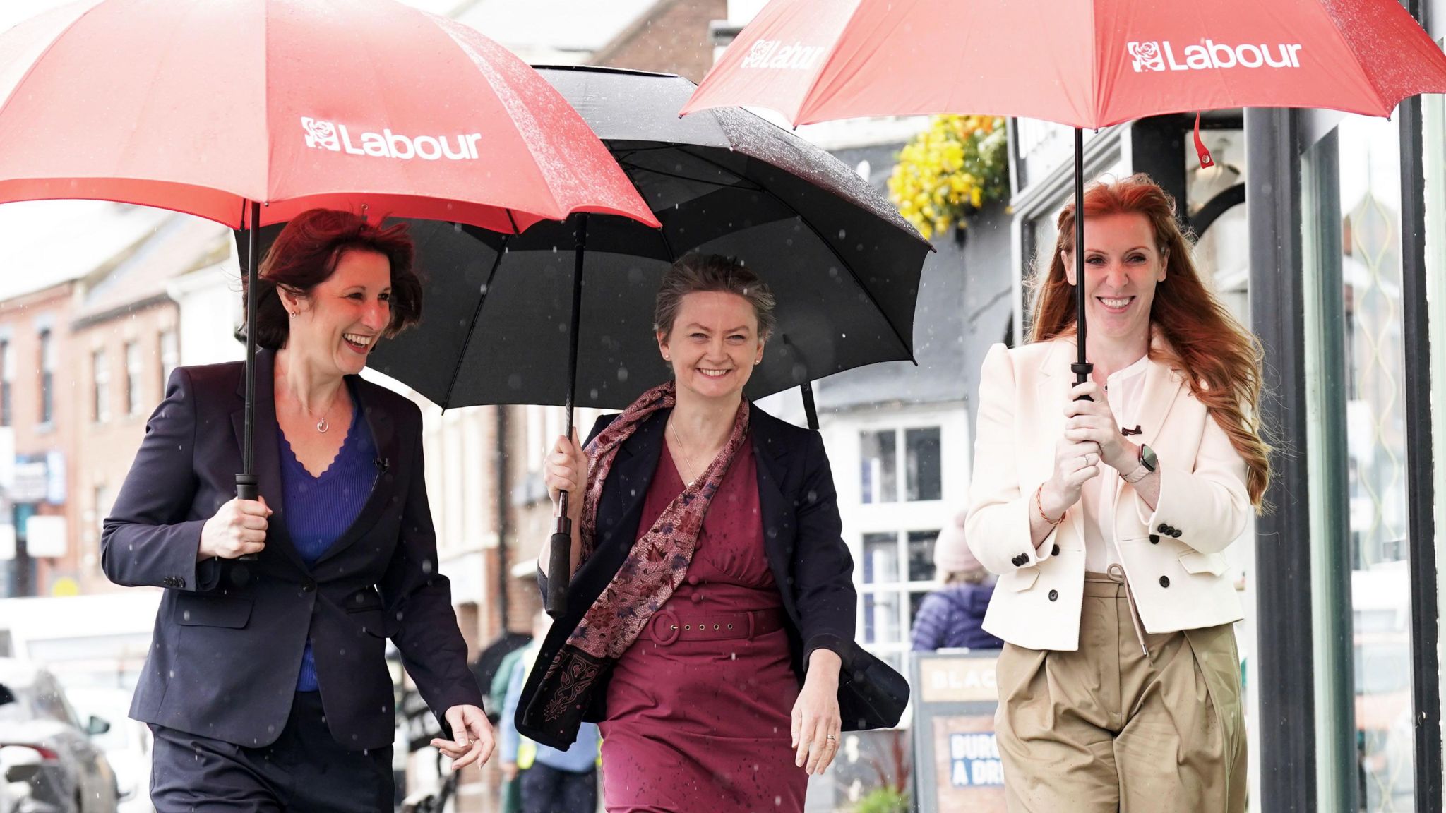 From left to right, Rachel Reeves, Yvette Cooper and Angela Rayner shelter under umbrellas in the Yarm rain