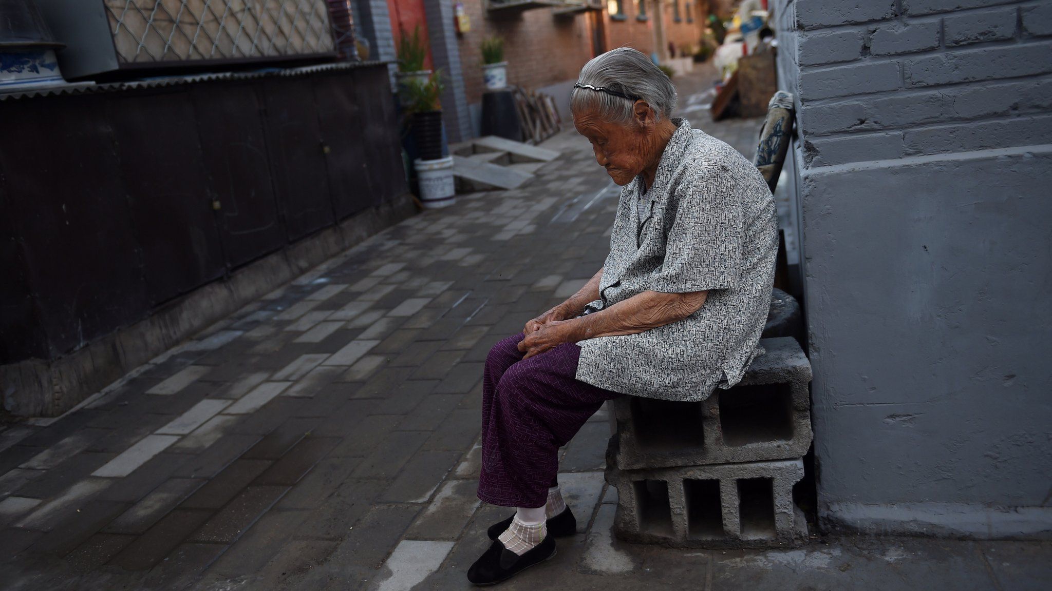 Elderly woman sits outside her home in west Beijing, China