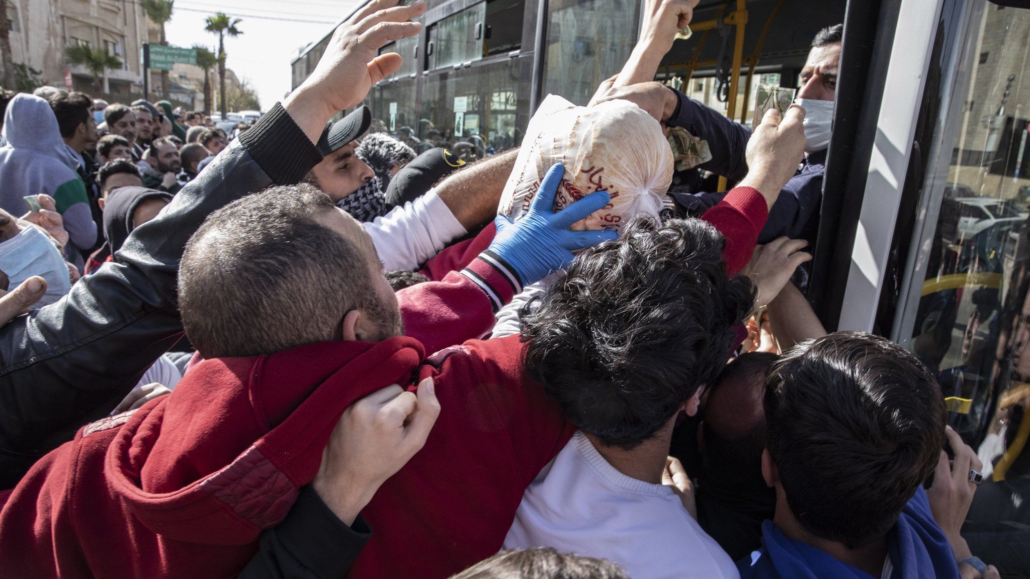 People try to collect bread from municipal buses in Amman, Jordan (24 March 2020)