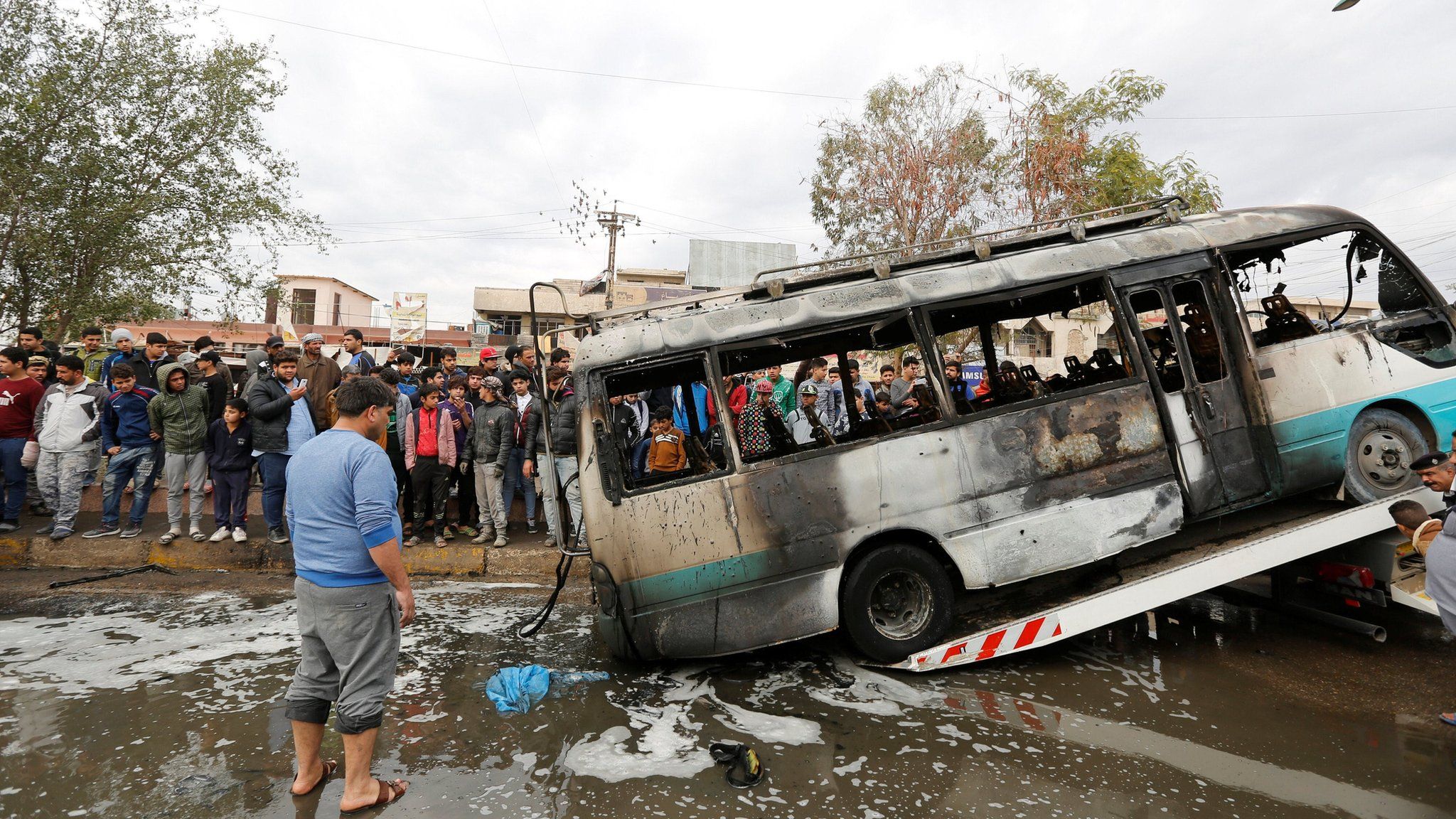 A burned bus is removed from the the scene of a suicide car bomb attack in Sadr City, Baghdad (2 January 2017)
