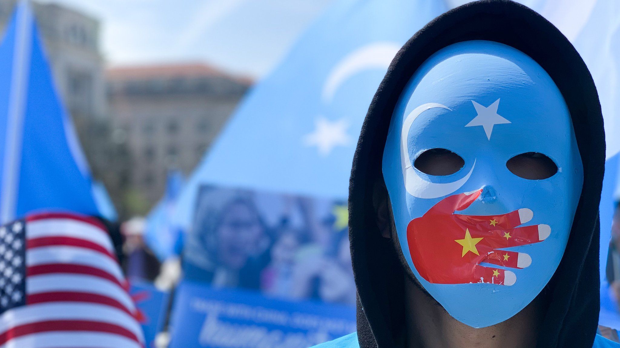 A demonstrator, wearing a mask with a Chinese flag on a hand over the mouth, protests in Washington