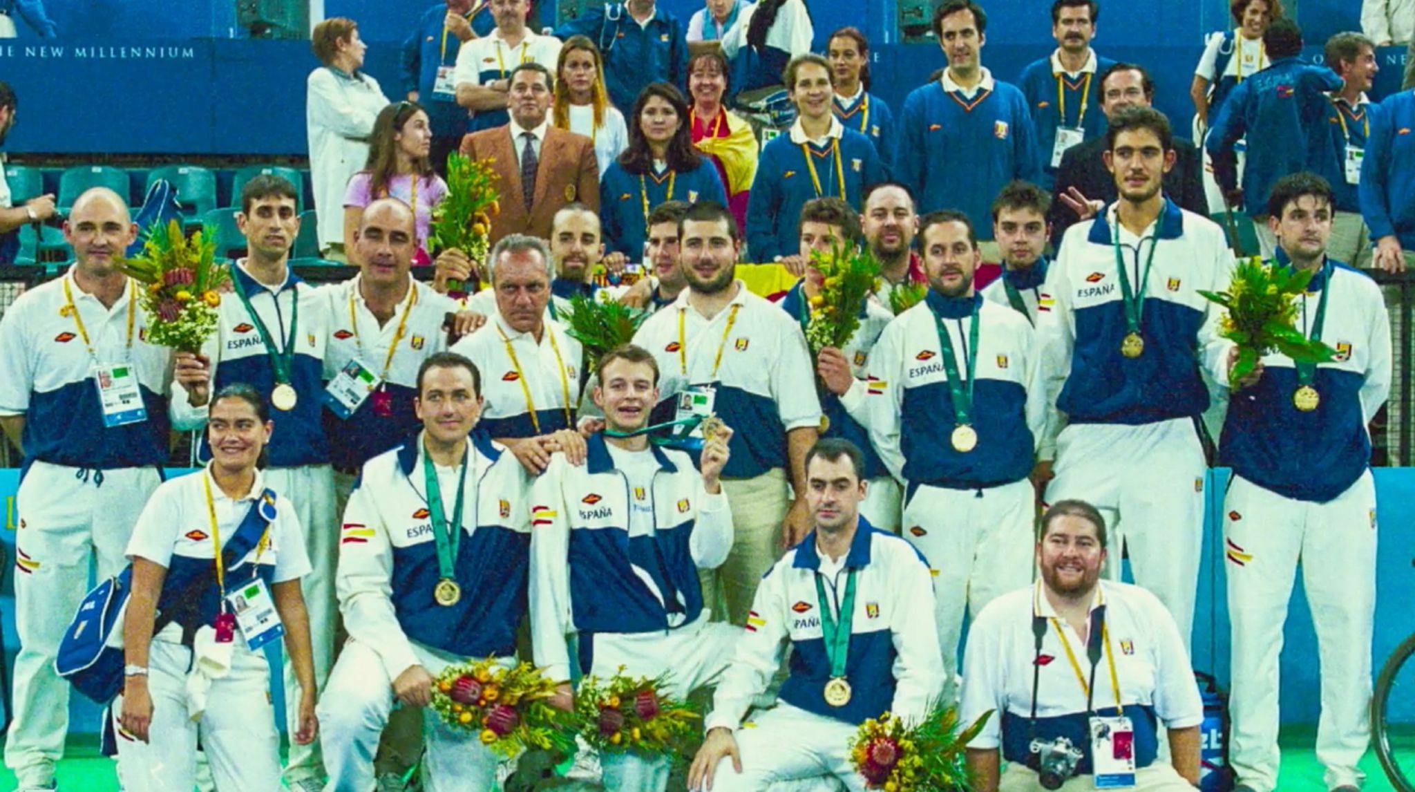 The basketball team wearing the gold medals they had to return - Fernando Martín Vicente can be seen in a brown jacket, standing behind the players