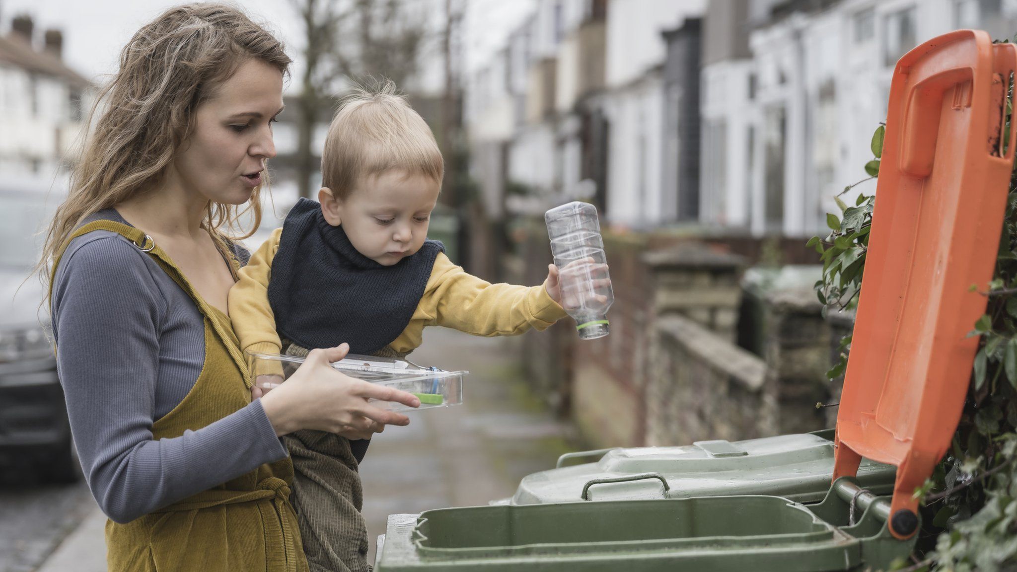 Woman and child putting recycling in a bin