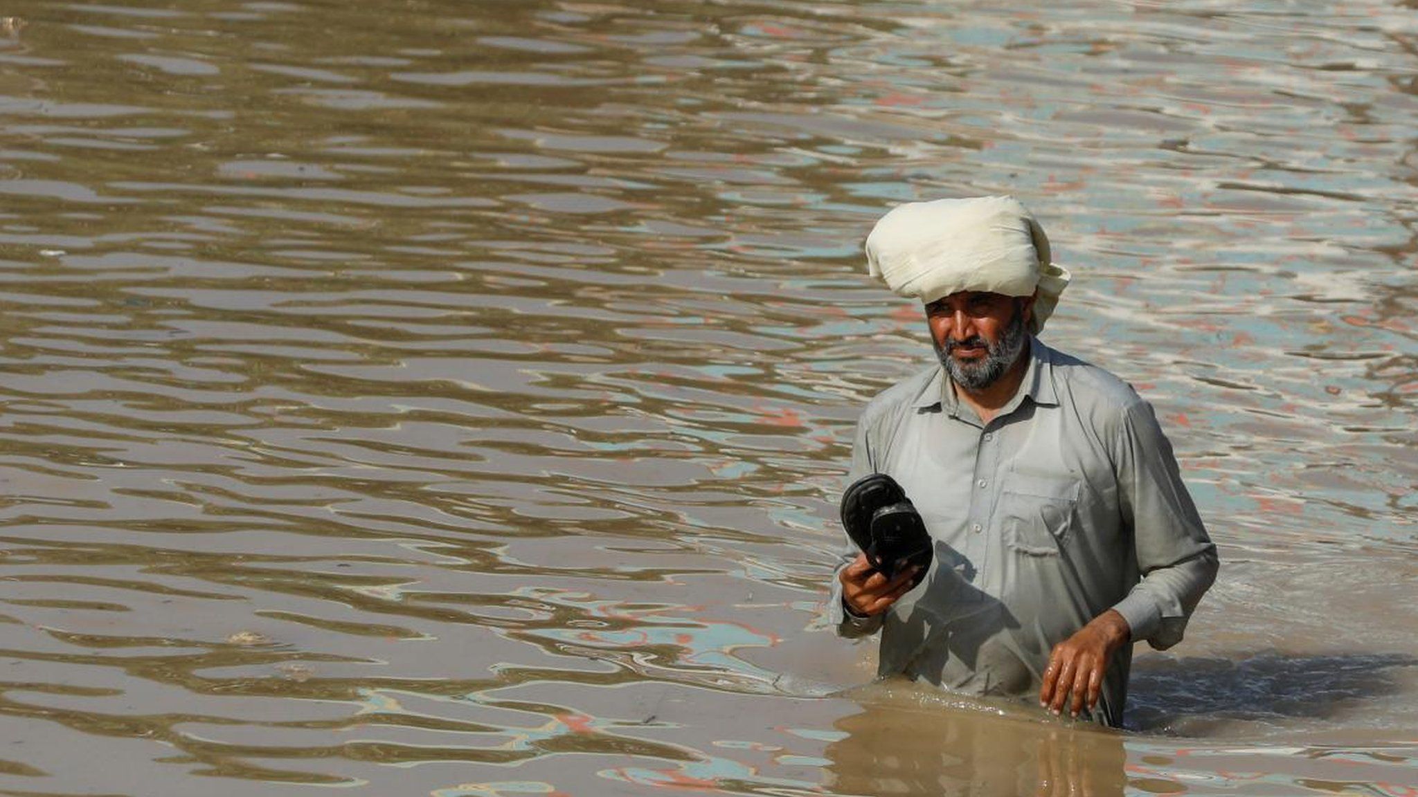 A man wades along a flooded road, following rains and floods during the monsoon season in Nowshera, Pakistan August 29, 2022.