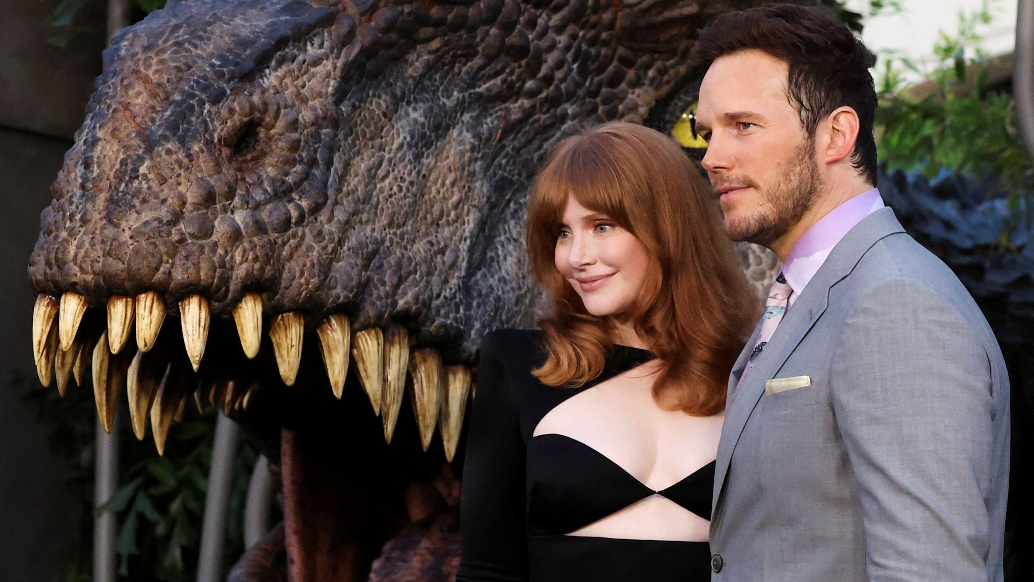 Bryce Dallas Howard and Chris Pratt posing in front of dinosaur jaws premiere for Jurassic World Dominion