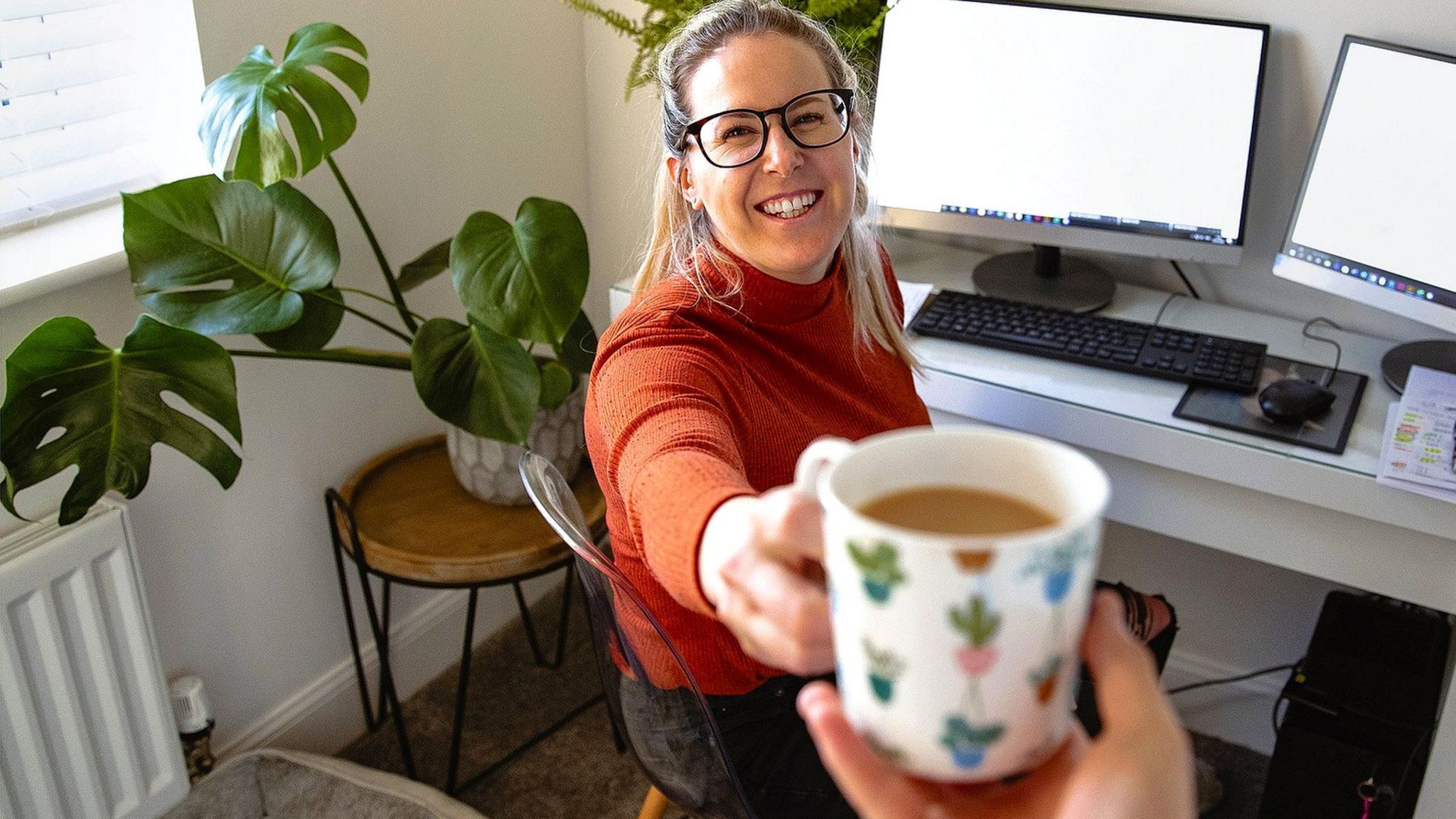 Woman working from home and being handed a cup of tea