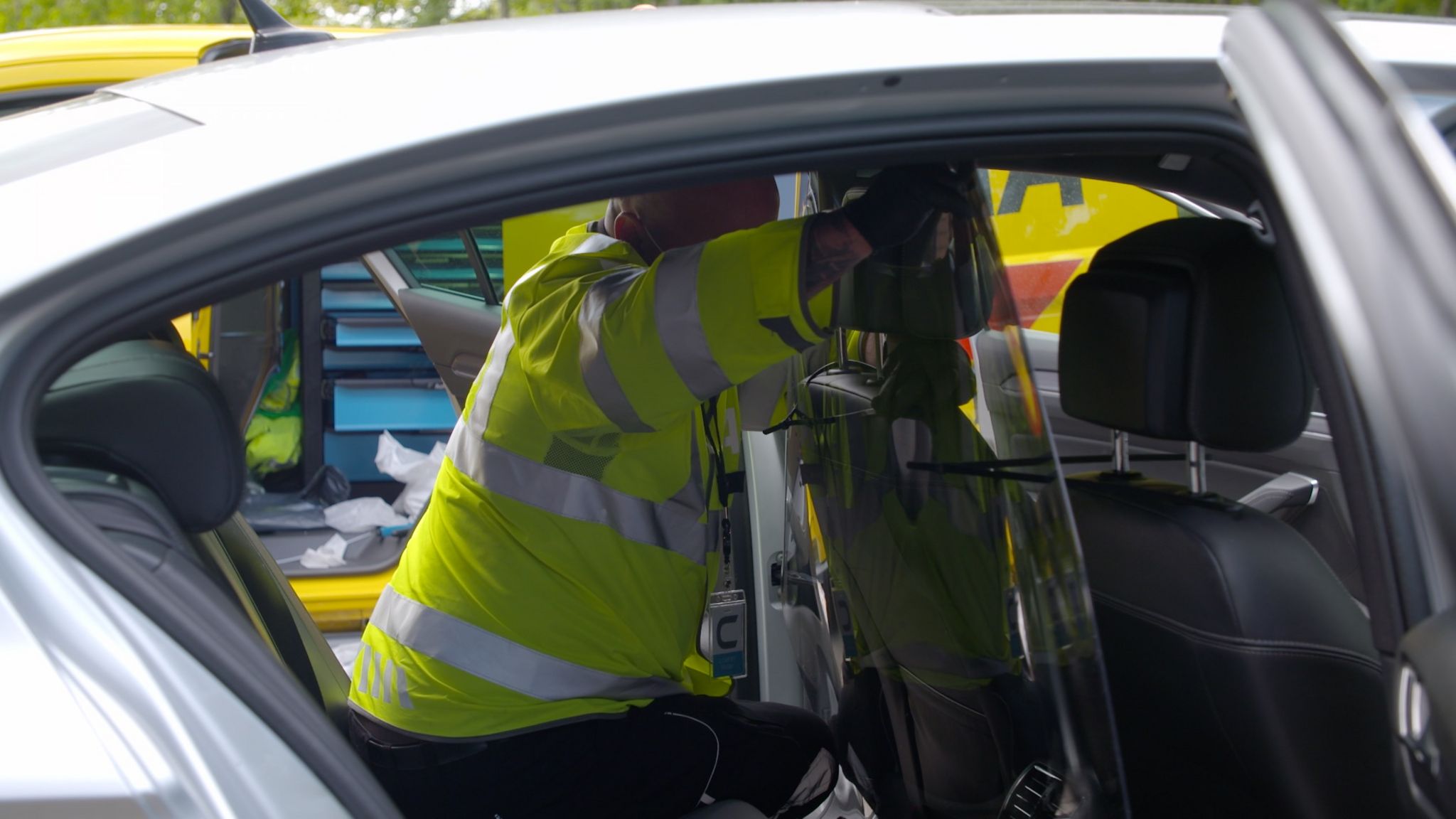An AA engineer installing a perspex screen in a taxi