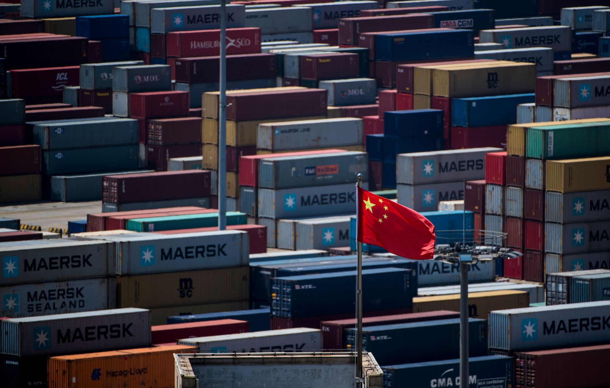 A Chinese flag is seen in front of containers at the Yangshan Deep-Water Port, an automated cargo wharf, in Shanghai on April 9, 2018.