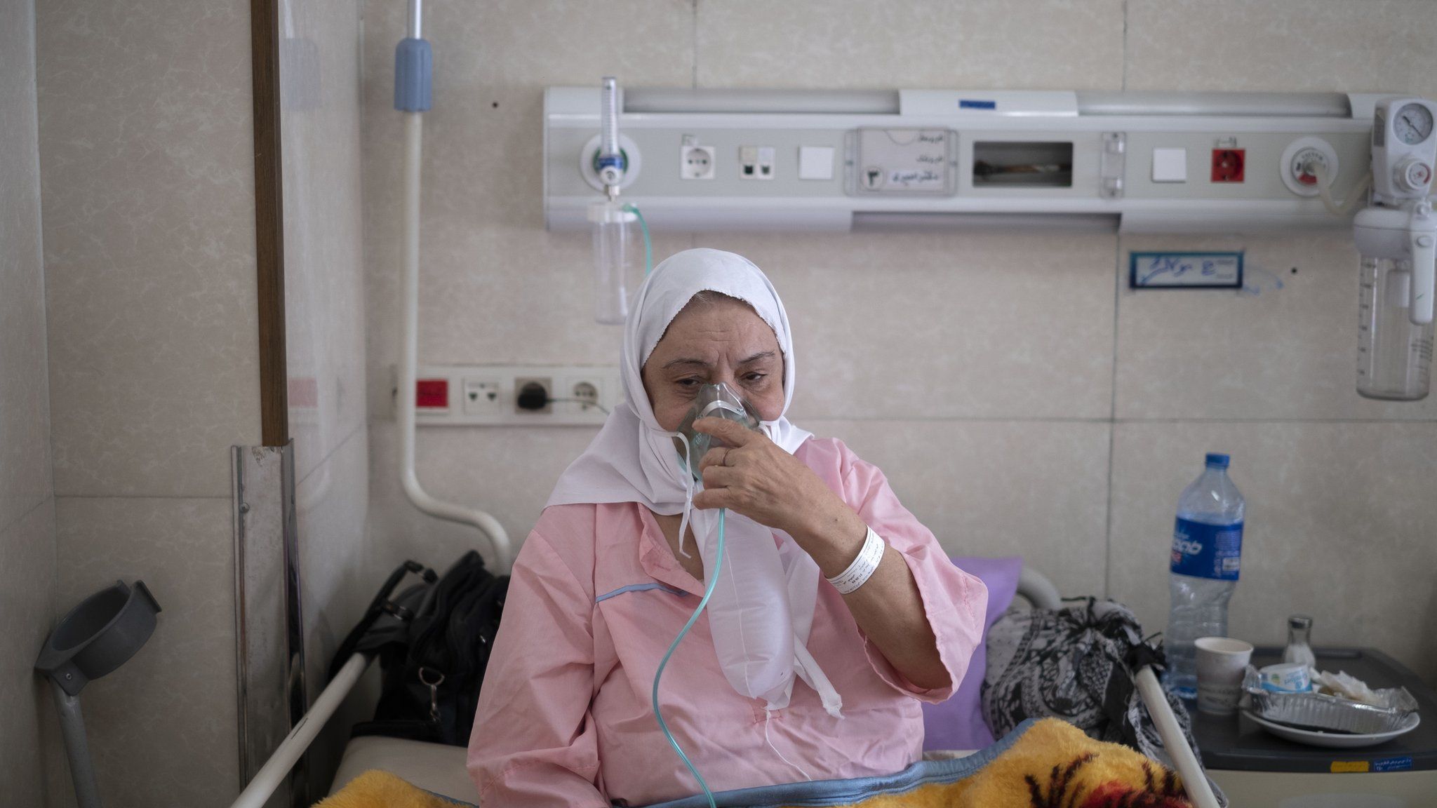 An Iranian elderly woman who is infected by Covid-19 uses oxygen while sitting on a hospital bed in the holy city of Qom in Iran, 10 March 2022.
