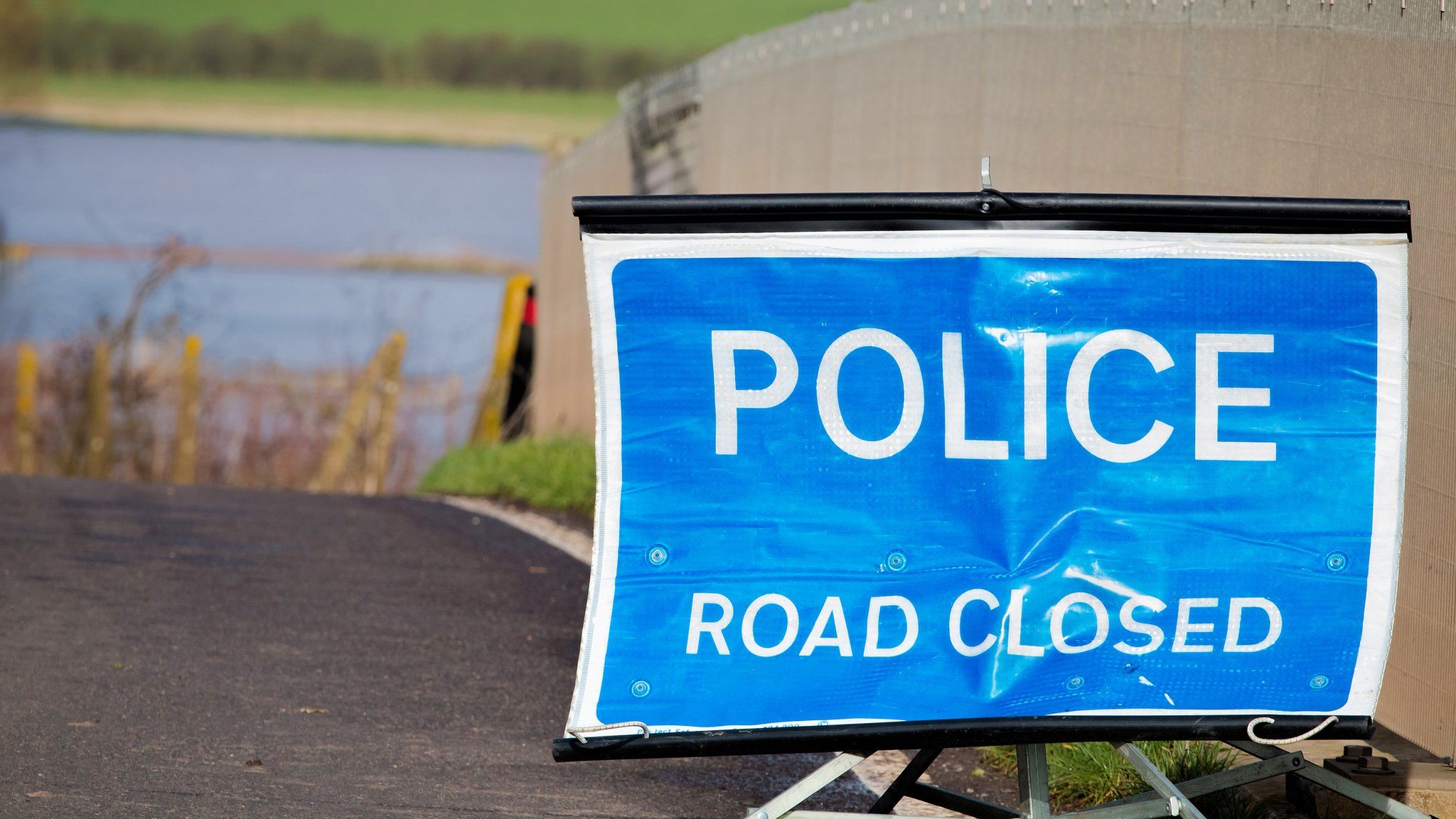 A police sign saying 'road closed' at the scene of an accident