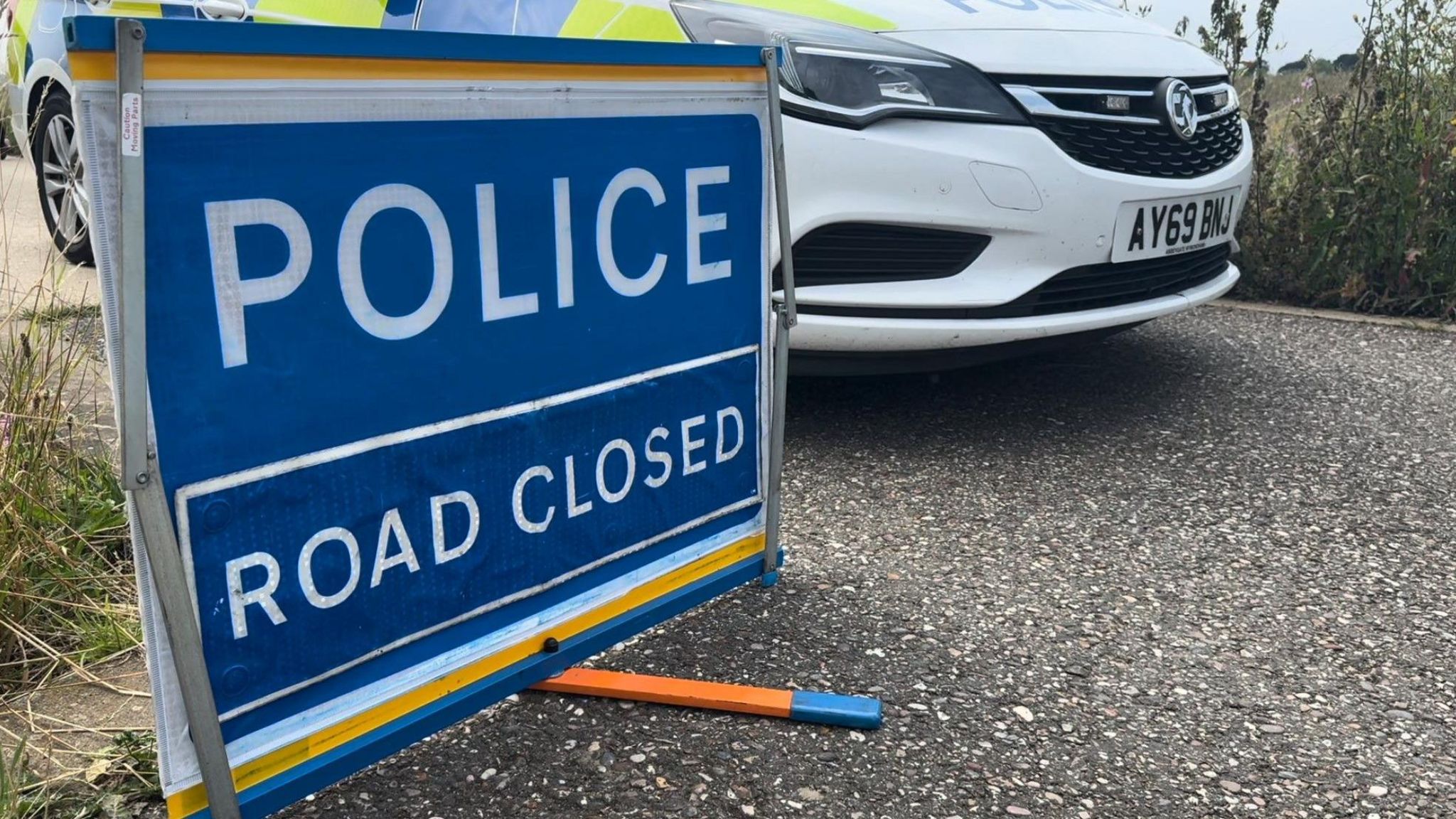 A sign reading "Police Road Closed" next to a police car